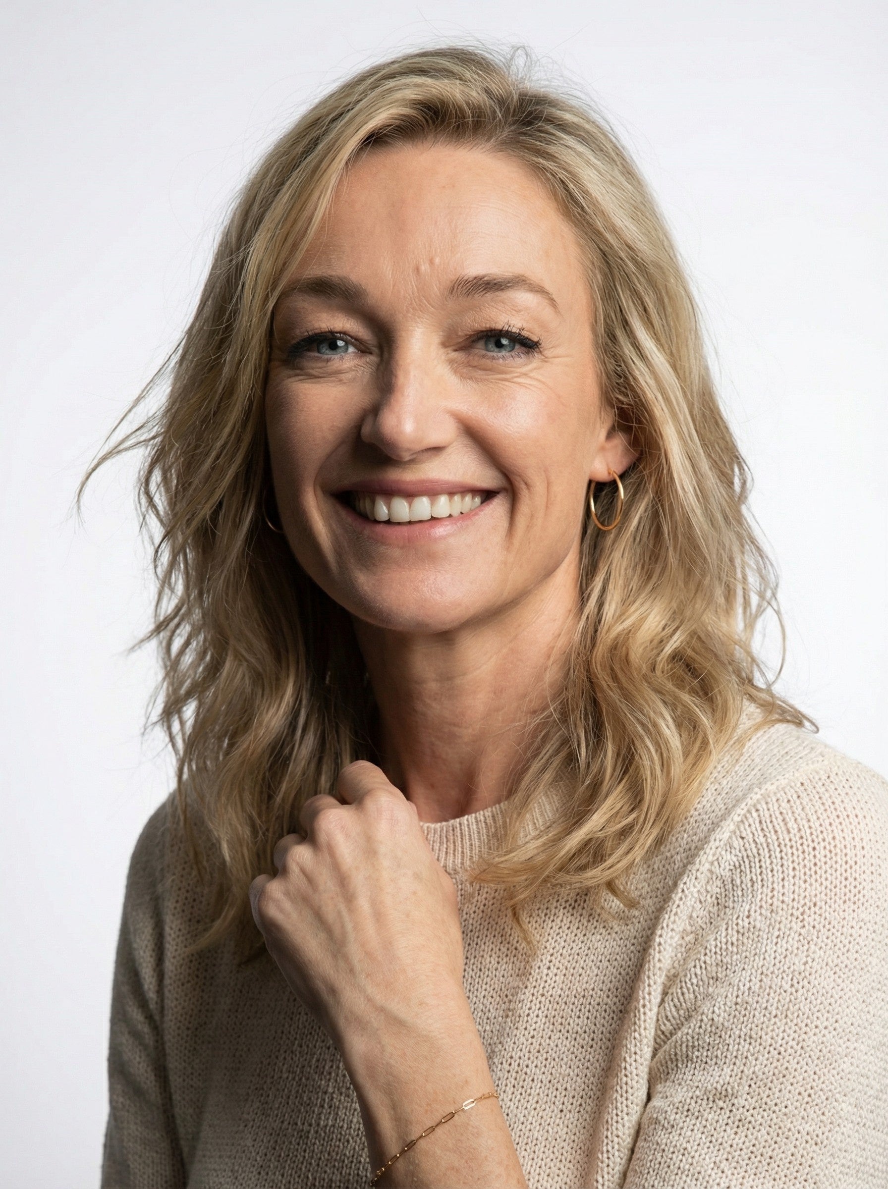 Woman with blonde hair smiling against a white background