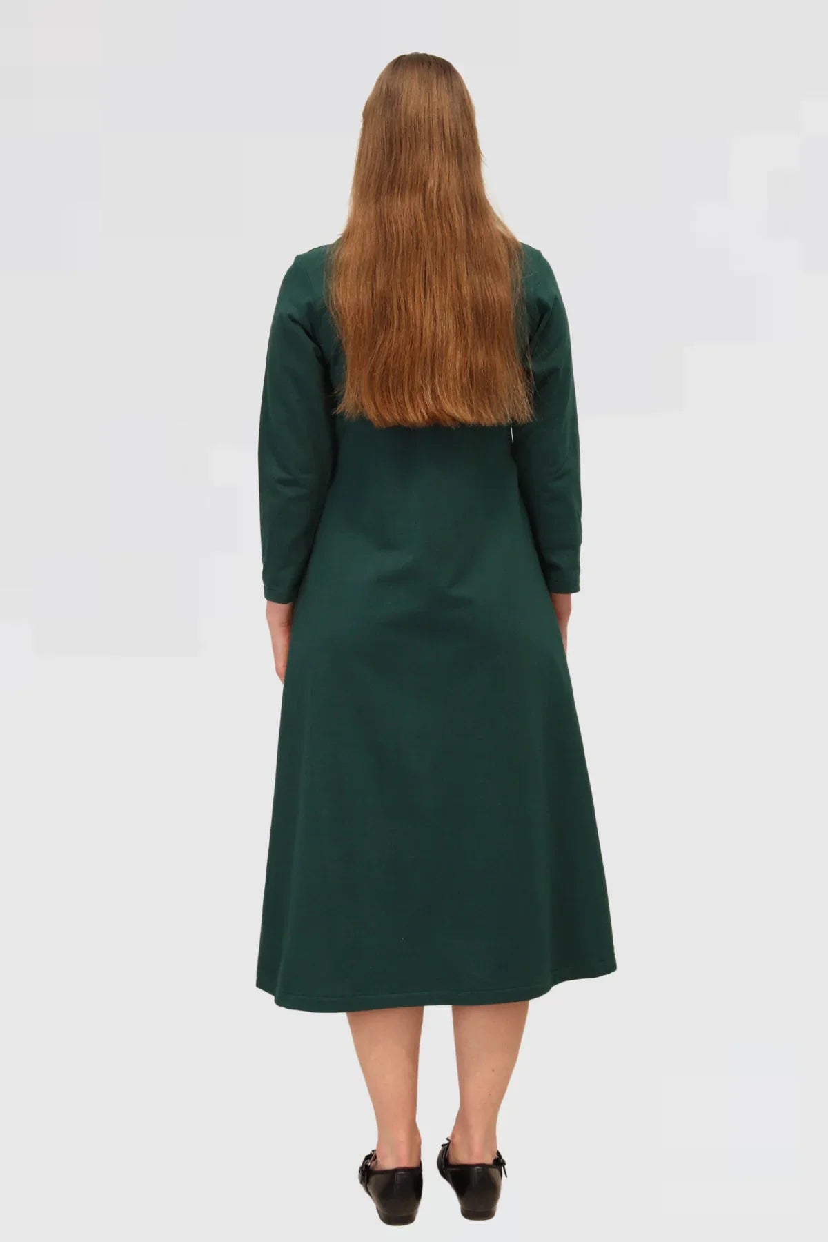 Woman wearing a green dress from behind on a plain background