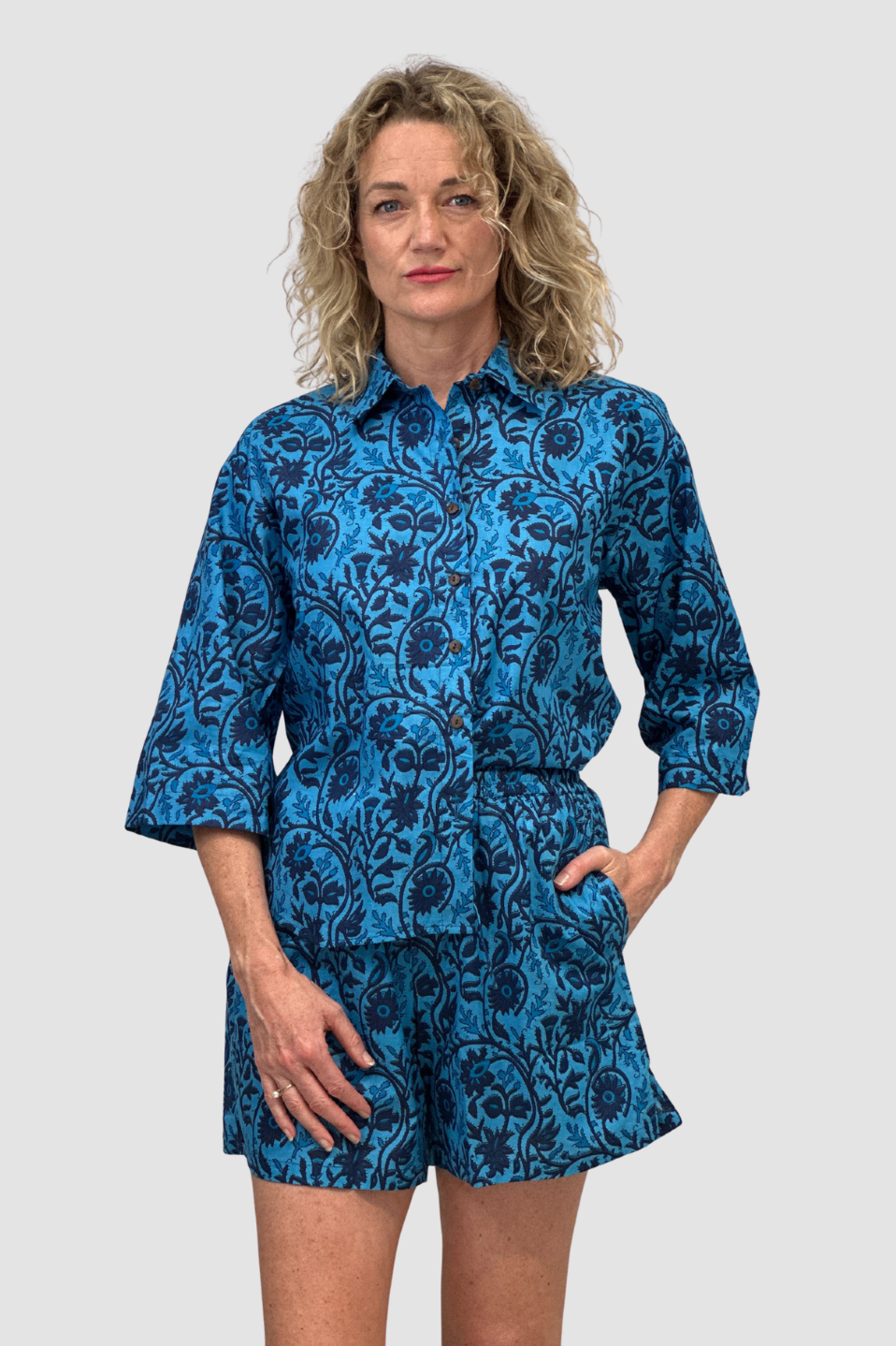 Woman wearing a blue patterned shirt and shorts, named the "Indigo Tide Cotton Lounge Shorts" set on a plain background