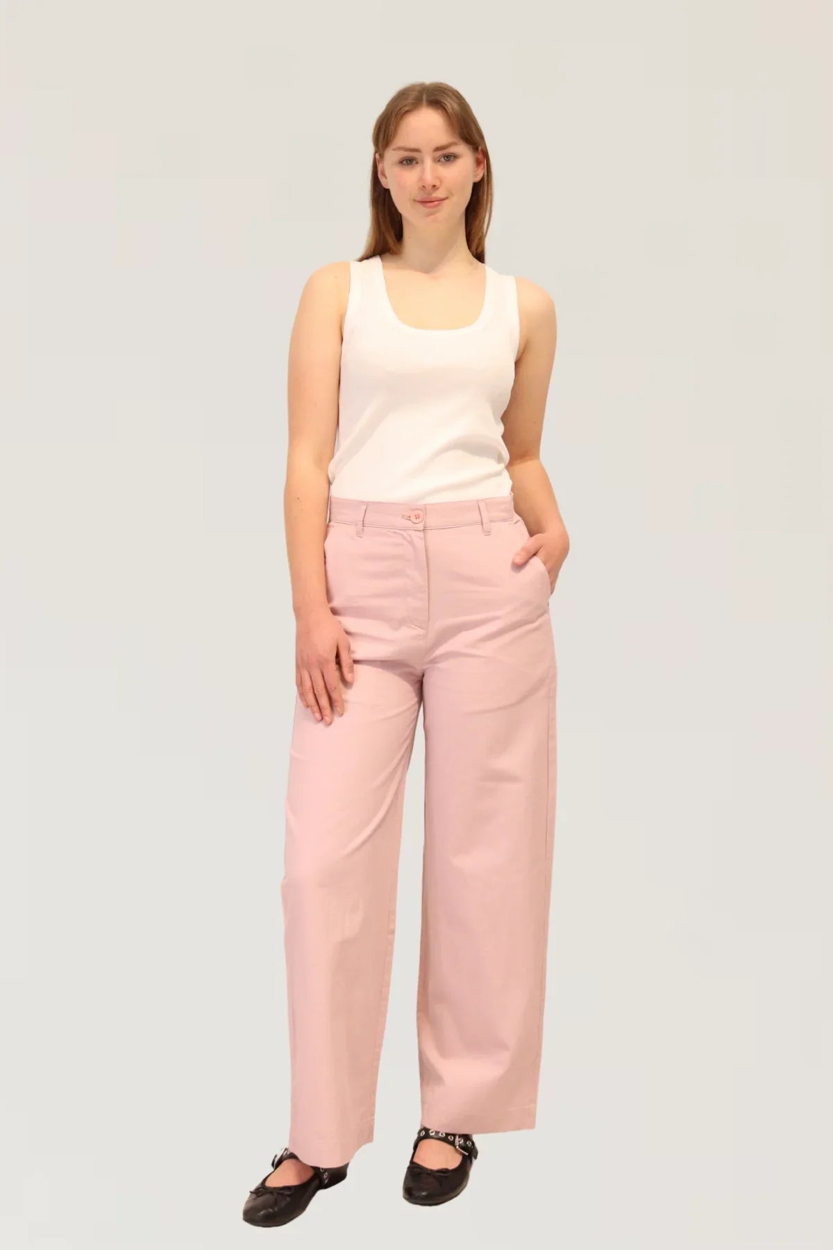 Woman wearing a white sleeveless top and pink pants 48% cotton, 29% TENCEL™, and 23% linen on a plain background