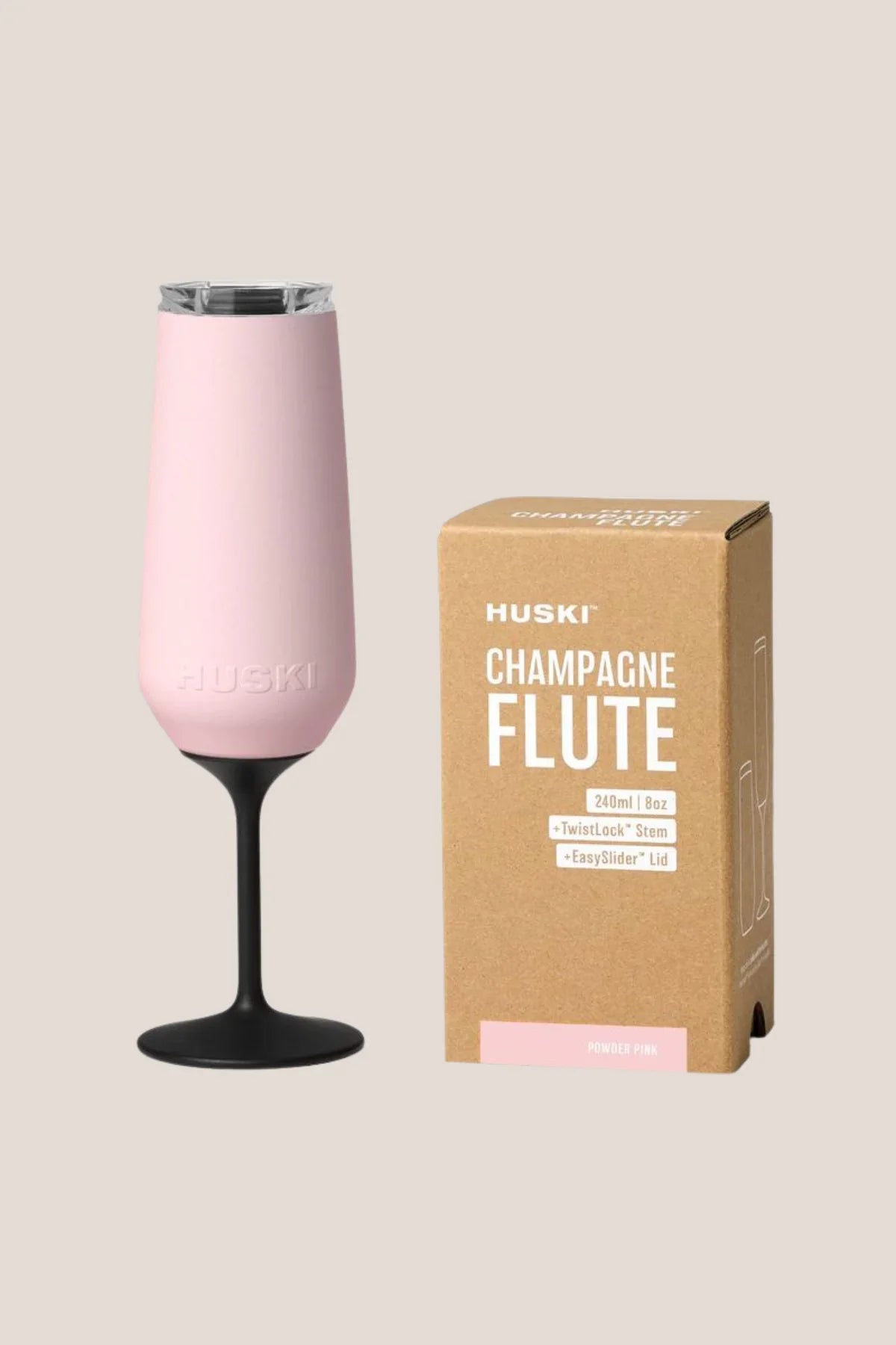 Pink champagne flute with black base next to its packaging on a beige background