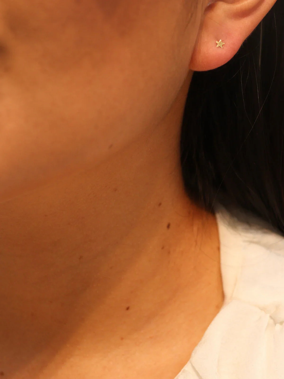 Close-up of an ear with a gold star-shaped earring.