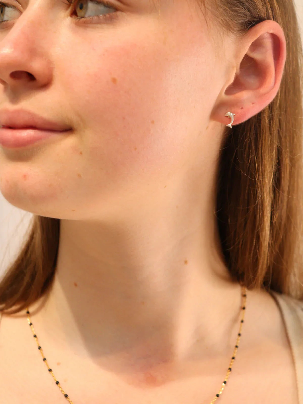 Woman wearing silver dolphin stud earrings.