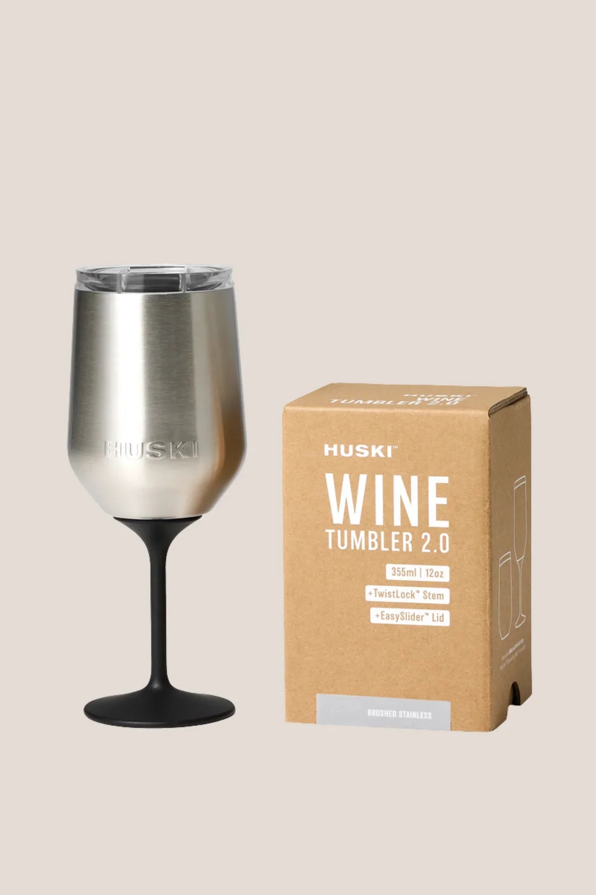 Silver wine tumbler with black base next to its packaging box on a beige background