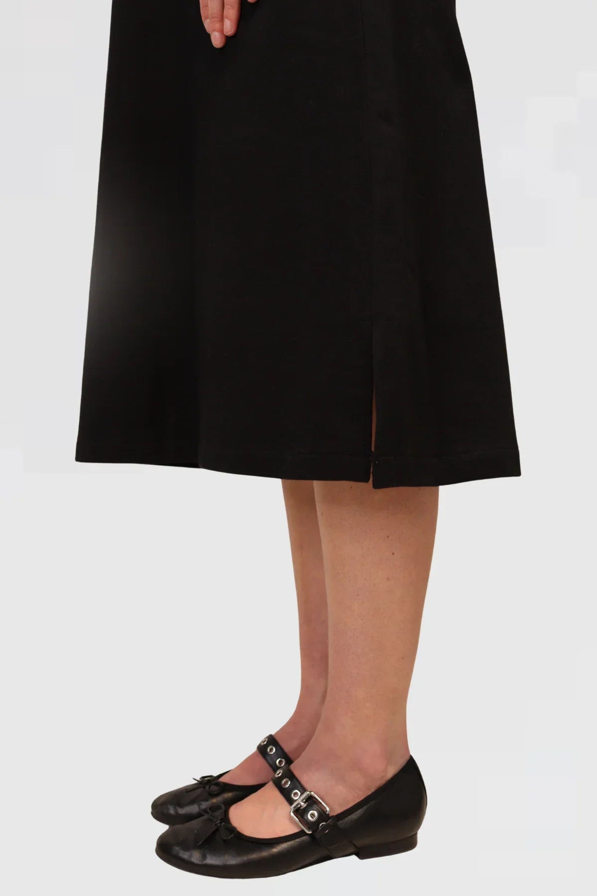 Person wearing a black dress and black shoes on a plain background