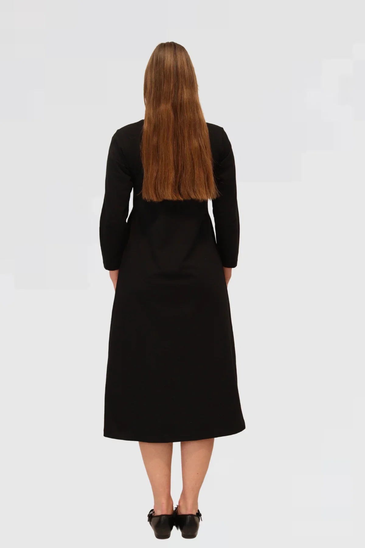 Woman wearing a black dress against a plain background