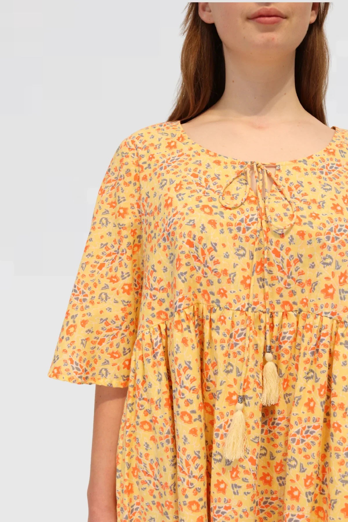 Yellow floral dress worn by a person on a light plain background. Made ethically from 100% natural cotton