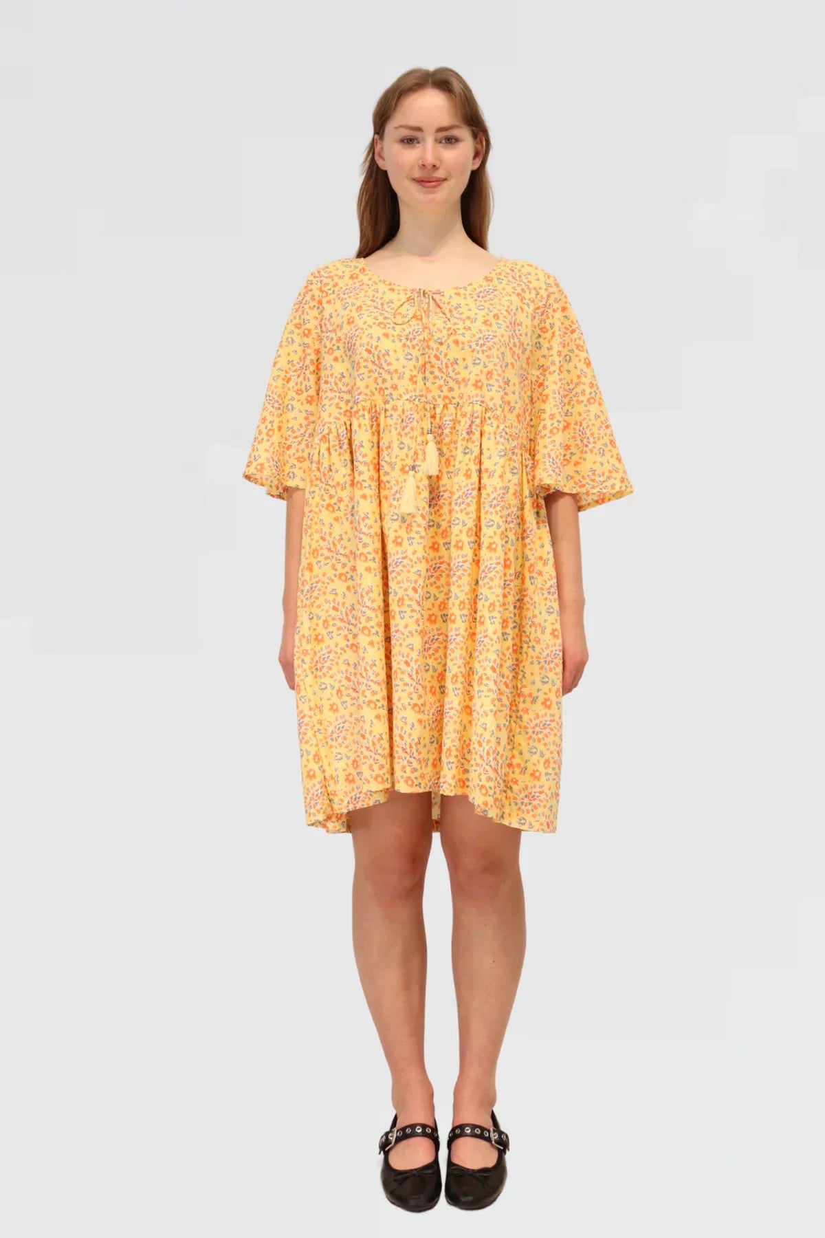 Woman wearing a yellow floral dress, Made ethically from 100% natural cotton on a white background
