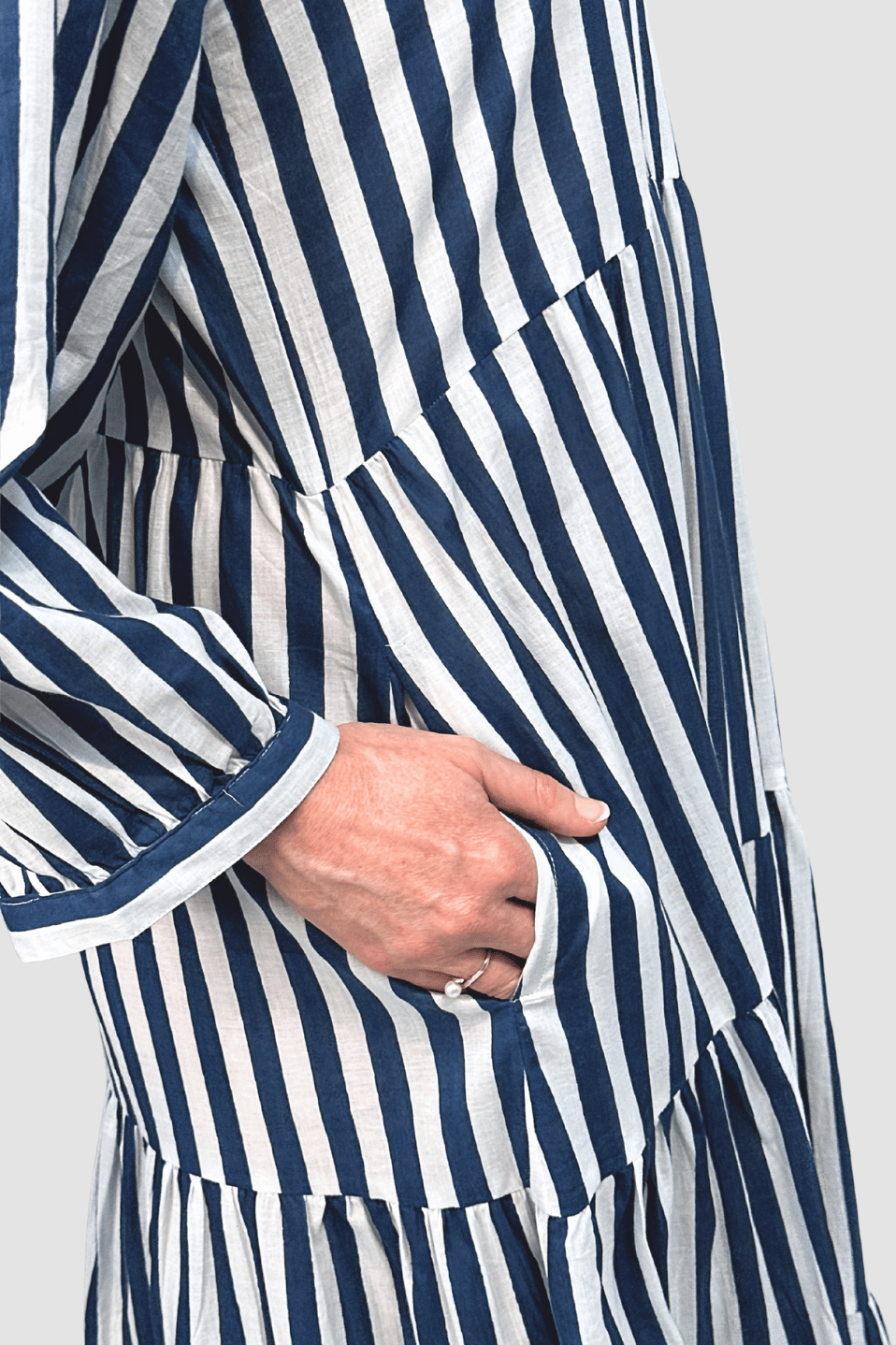Close-up of hand in pocket of blue and white striped ethical clothing dress with pearl ring