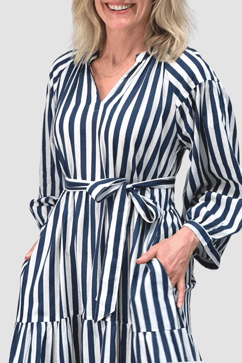 Smiling woman wearing blue and white striped belted dress with pockets, casual ethical fashion
