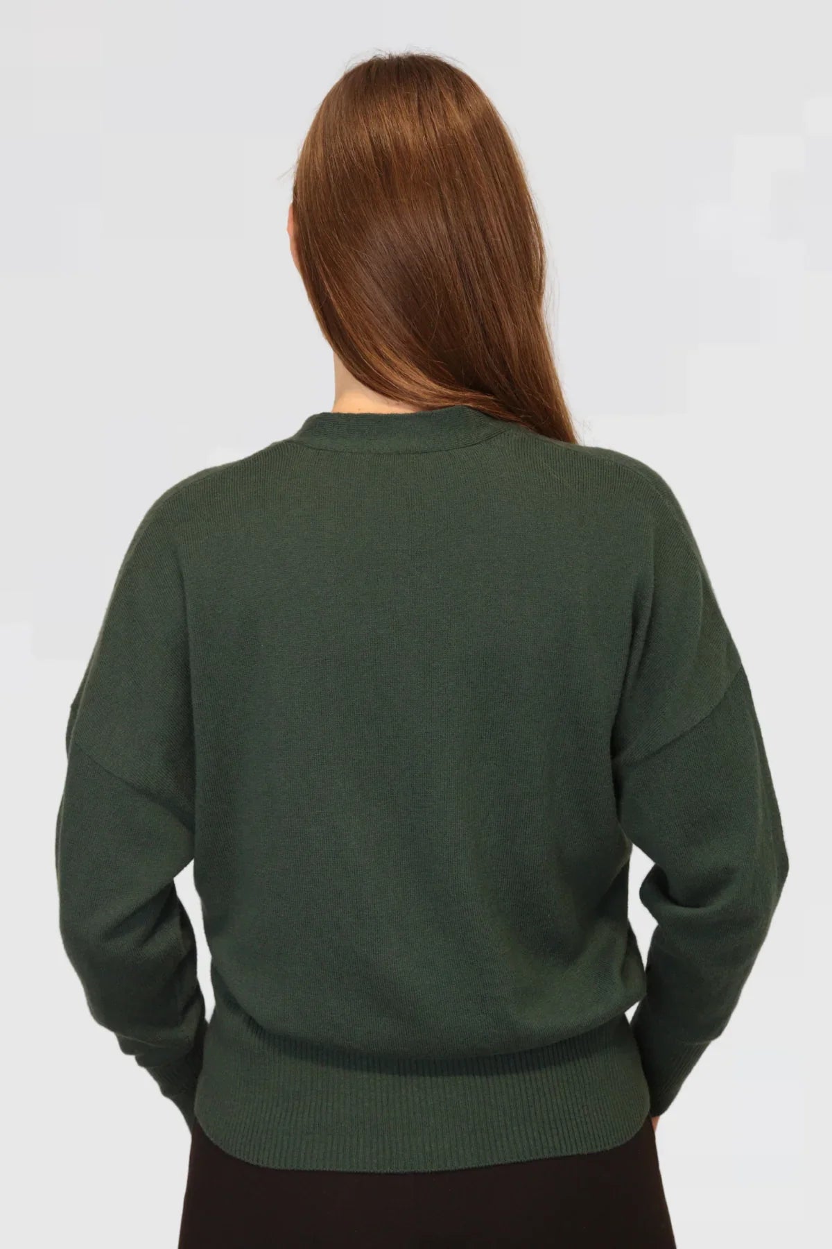 Person wearing a green sweater on a plain background
