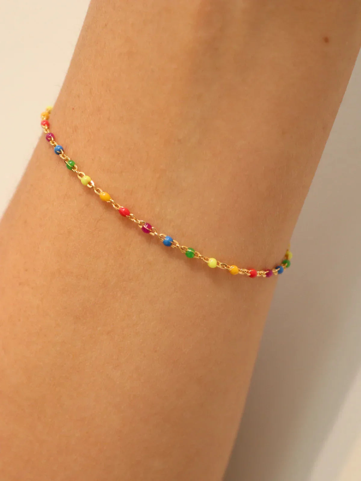 Colorful beaded anklet on a person's ankle against a neutral background