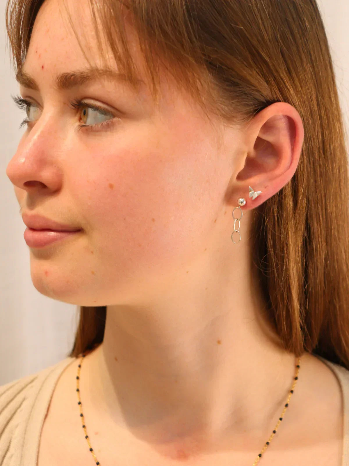 Model wearing sterling silver hoop drop earrings with butterfly stud, minimalist and modern style.