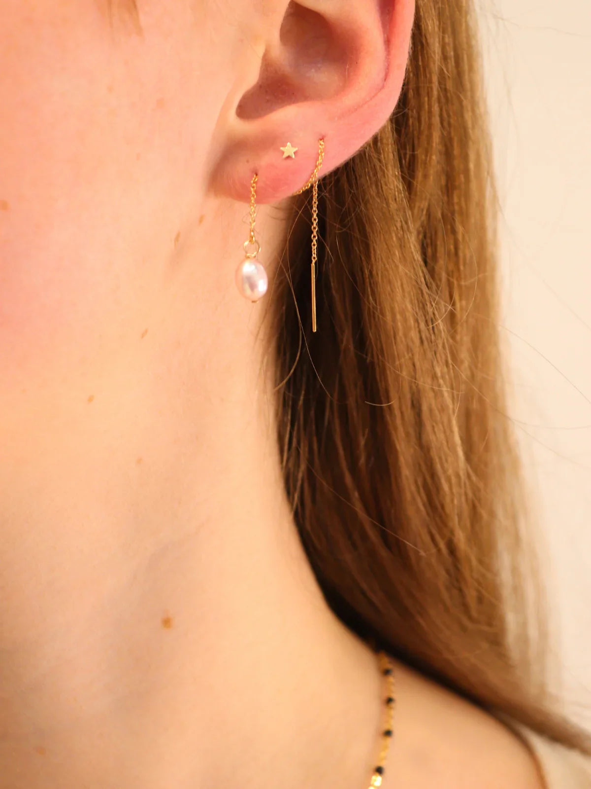 Side view of pink freshwater pearl threader earrings on gold chain, delicate handmade jewellery.