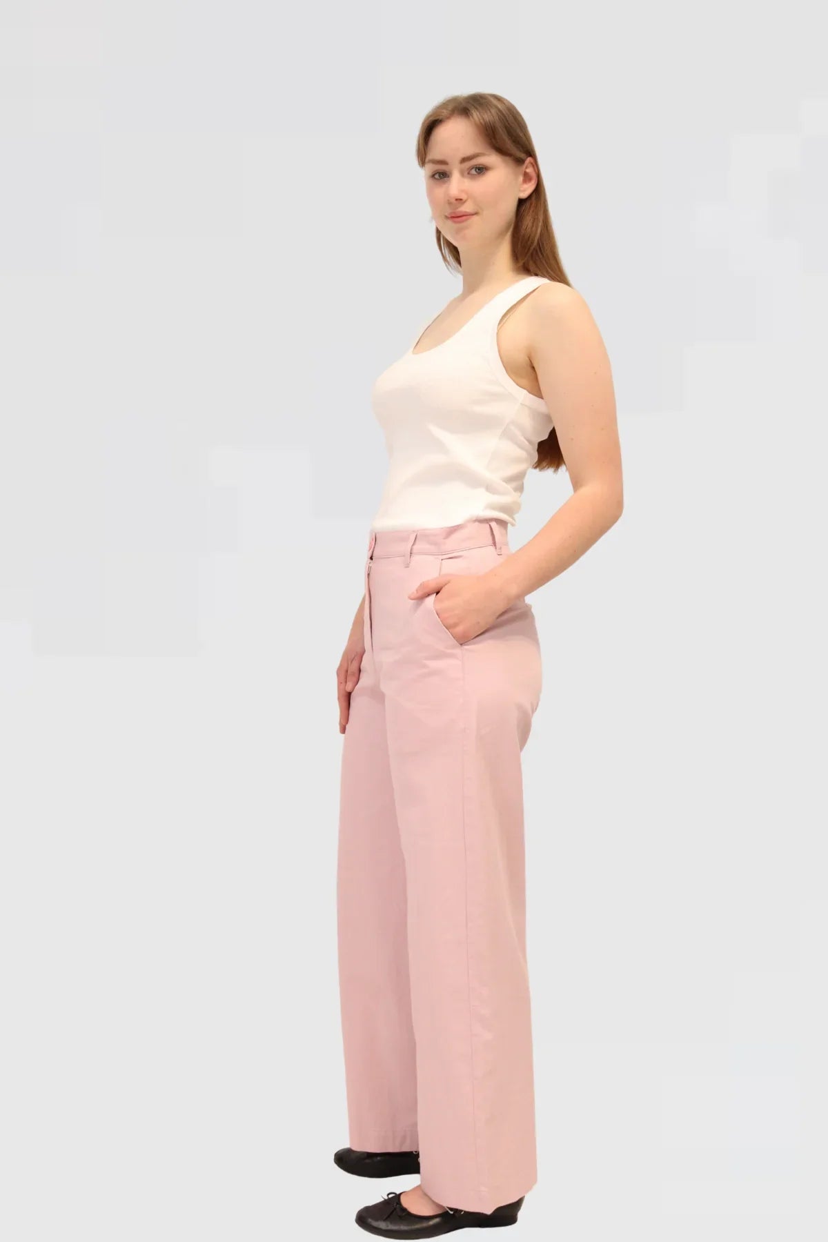 Woman wearing a white sleeveless top and pink pants 48% cotton, 29% TENCEL™, and 23% linen on a light grey background