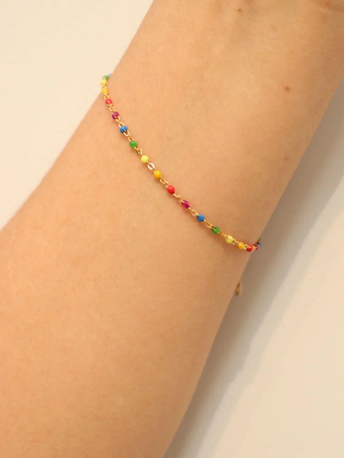 Multicolored beaded bracelet on a wrist against a neutral background