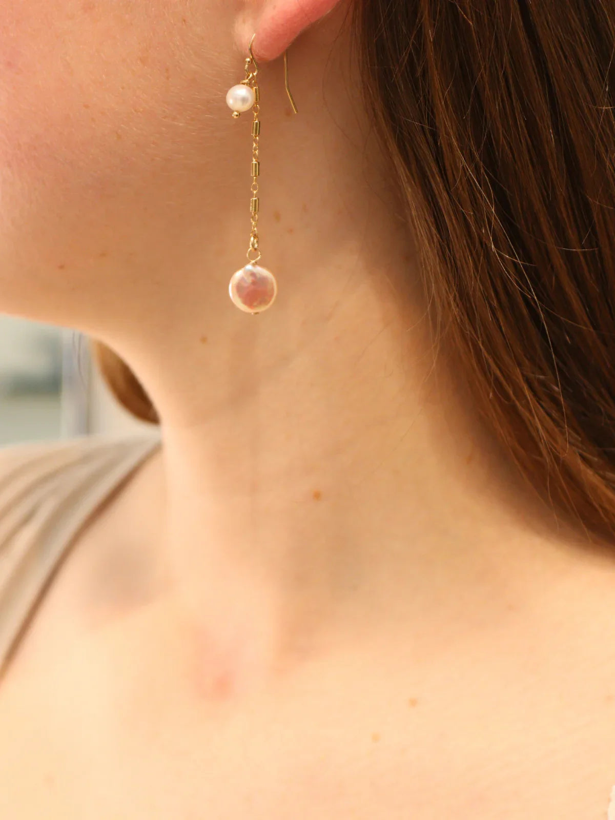 Delicate gold chain earring with round pearl and coin pearl, shown on ear.