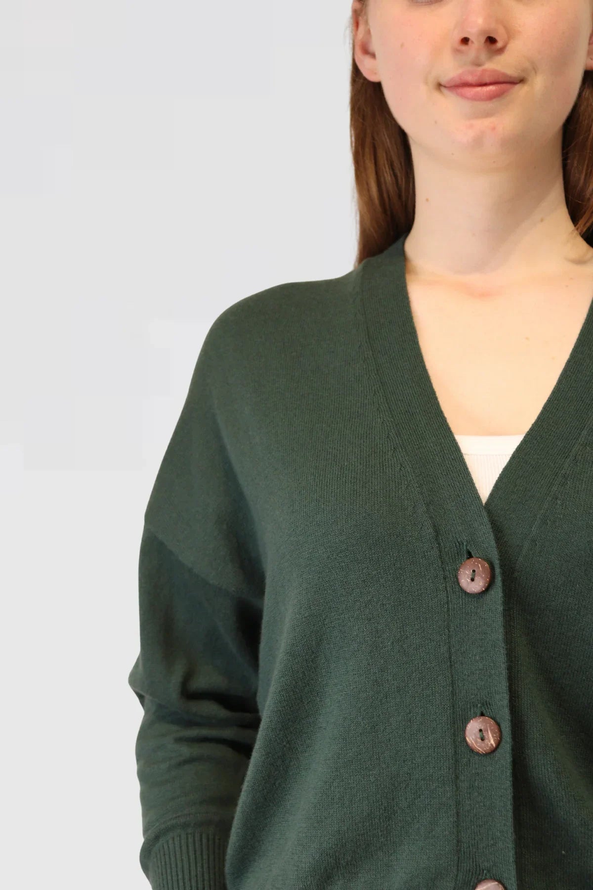 Person wearing a green cardigan with a plain background