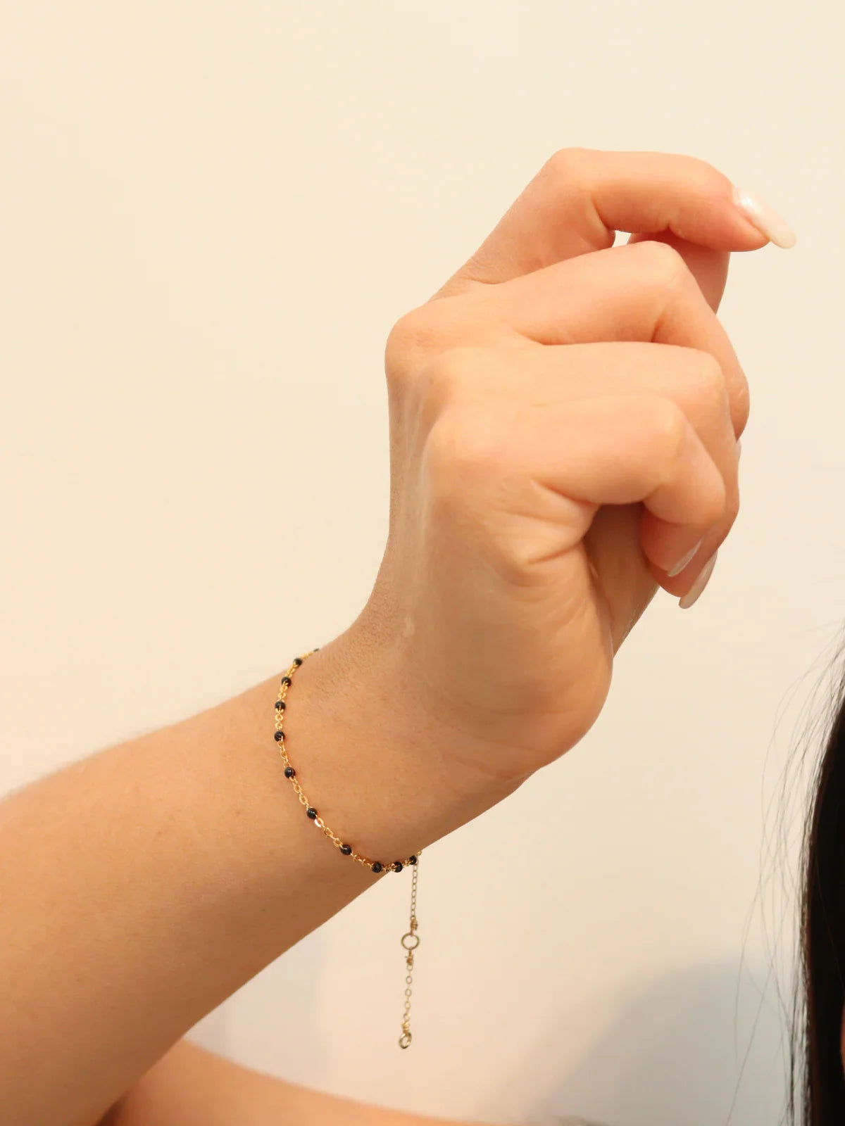 Hand wearing a beaded bracelet on a plain background