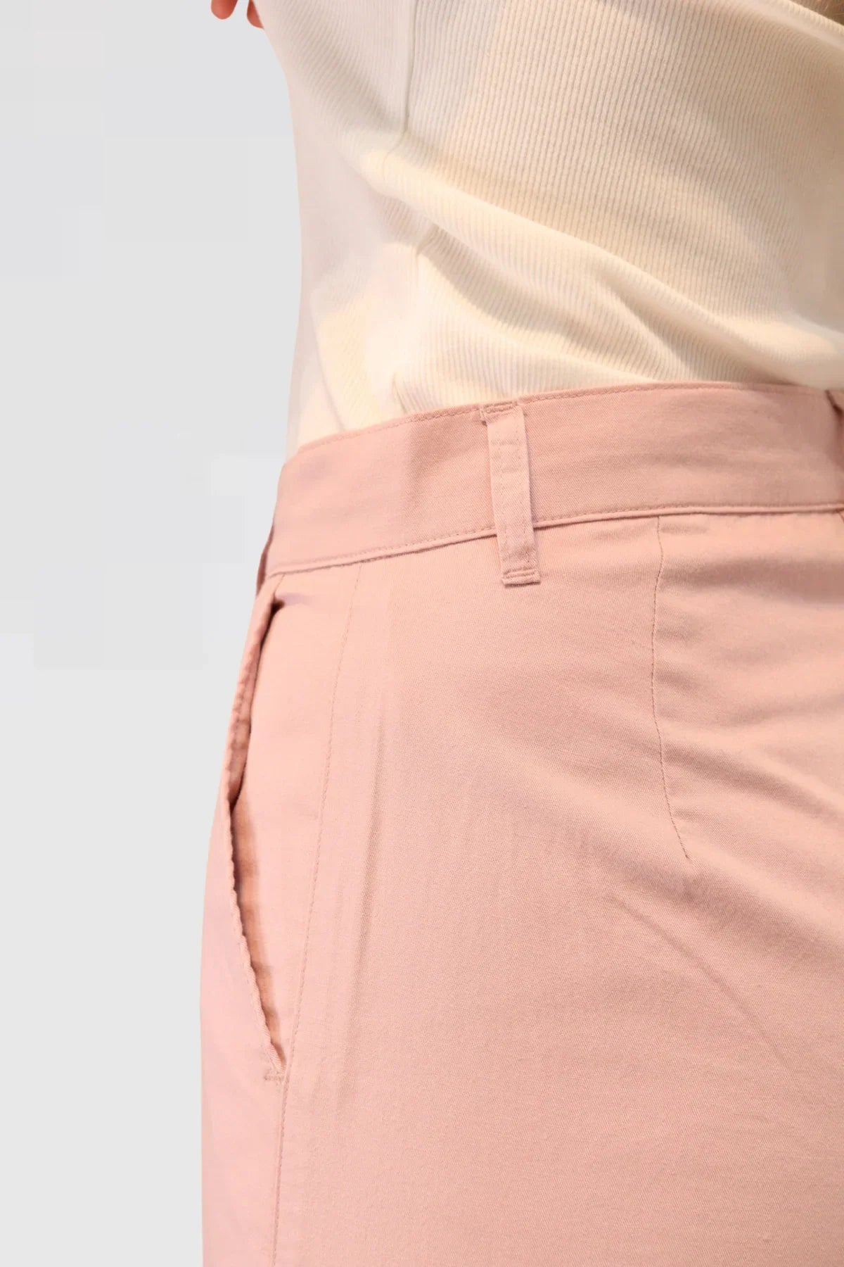 Close-up of pink pants 48% cotton, 29% TENCEL™, and 23% linen and a white top on a light grey background