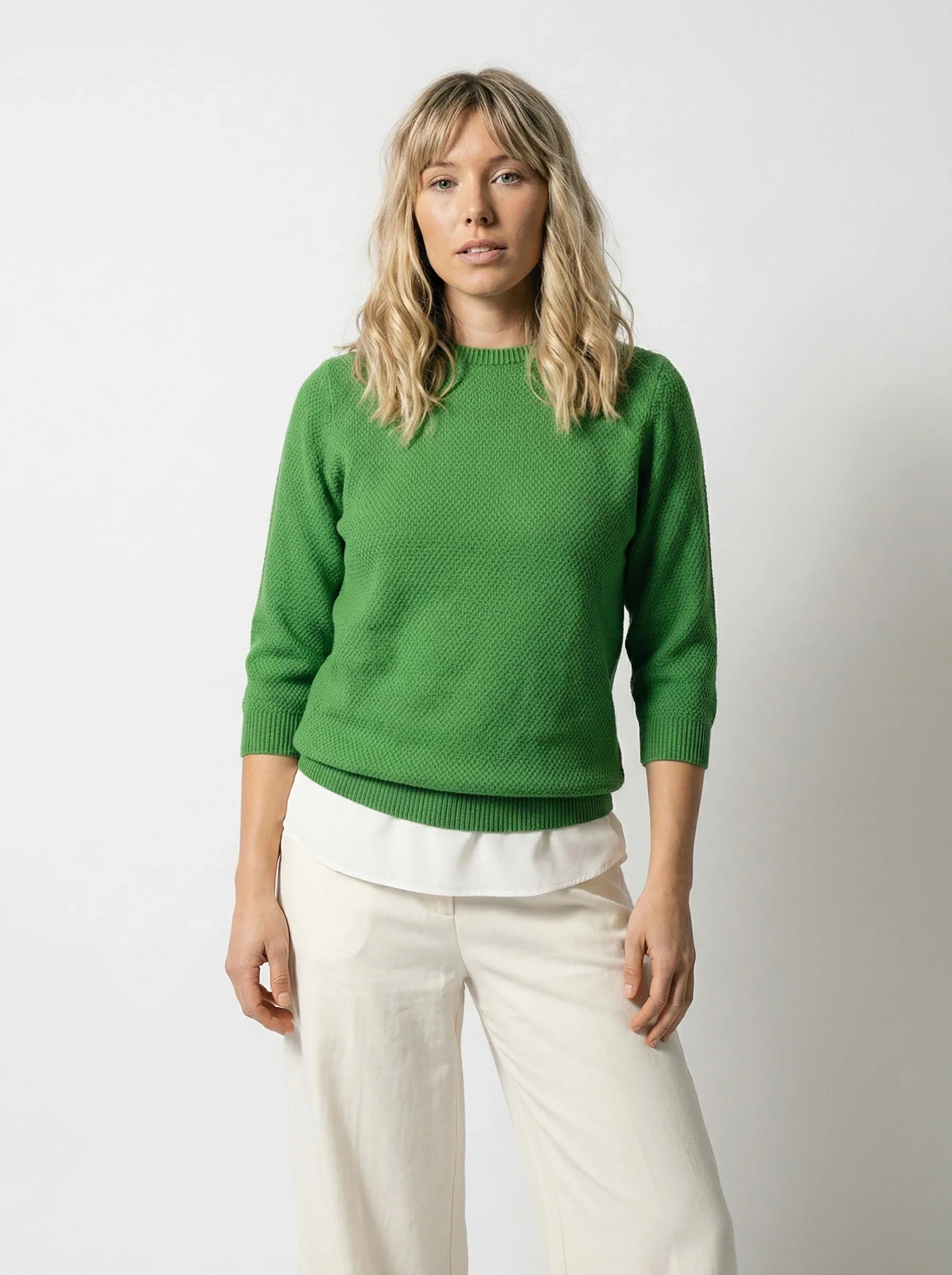 Model wearing Penny Textured Jumper in Kelly Green, a 50% Cotton 50% Merino knit with crew neckline and 3/4 sleeves, paired with cream wide-leg pants