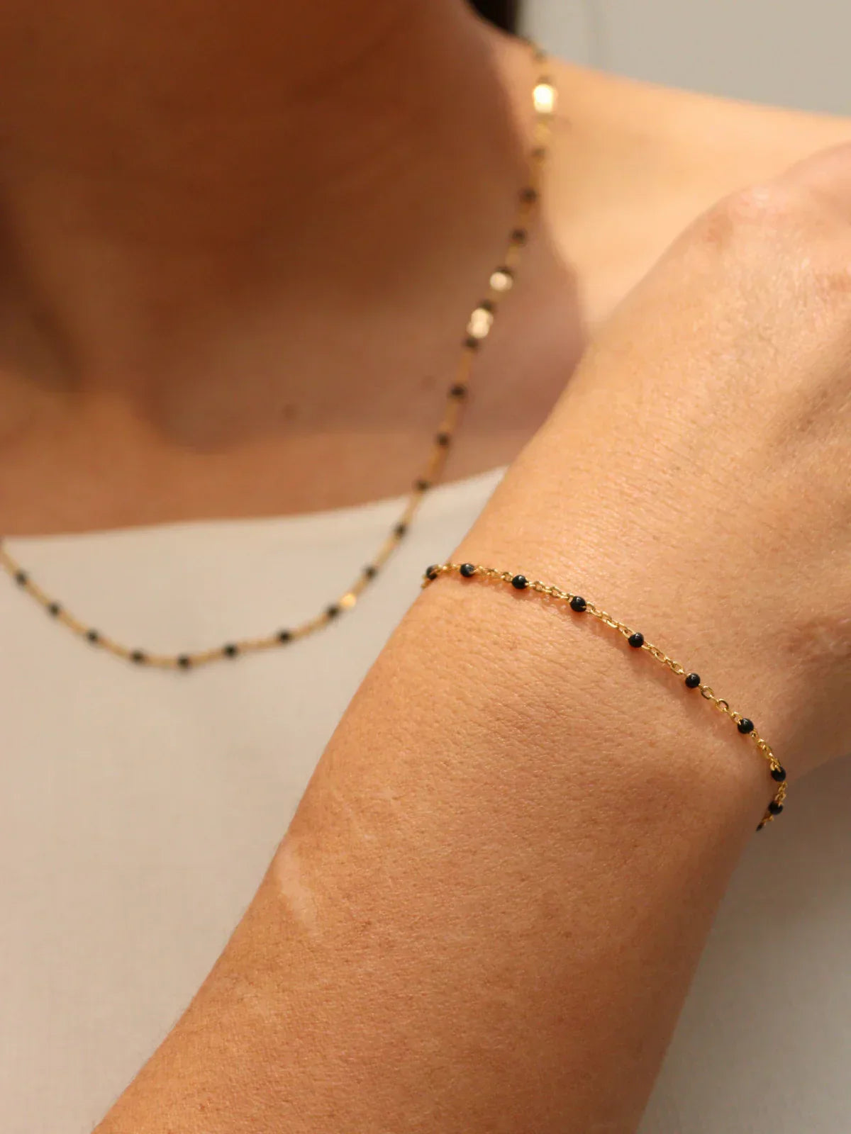 Matching gold black bead necklace and bracelet set, worn together.