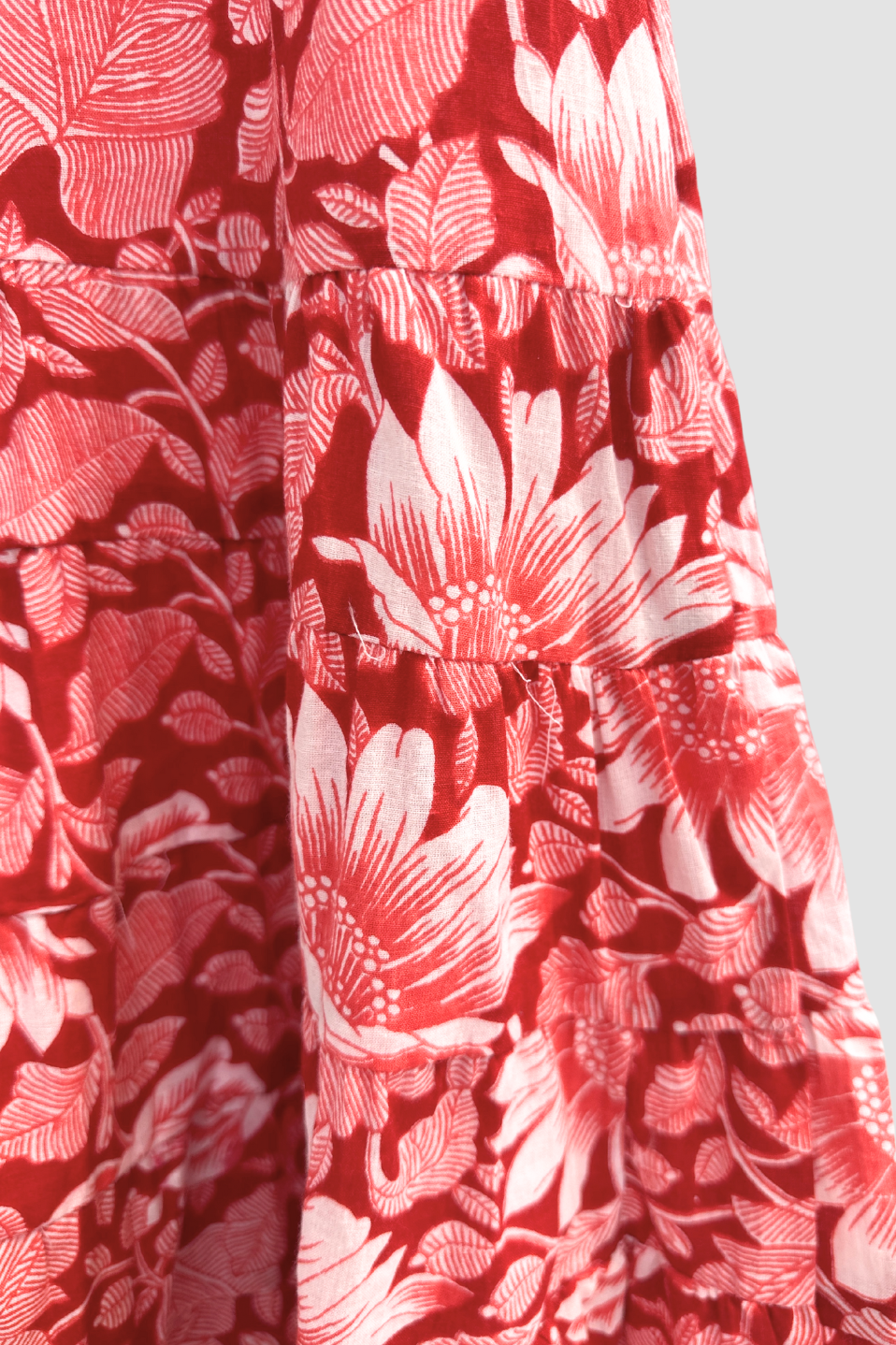 Close-up of red and white floral patterned ethical clothing fabric with gathered seam detail
