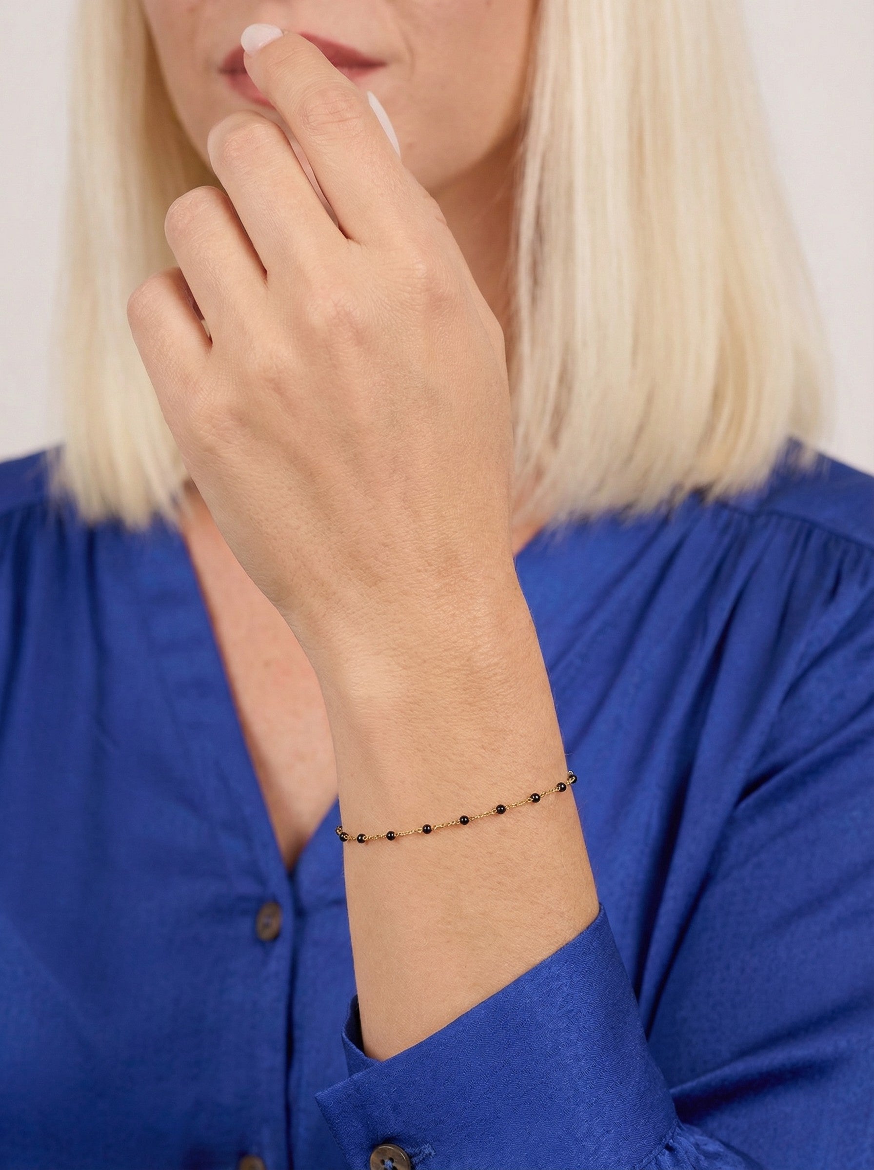 Person wearing a blue shirt with a Black Satellite bracelet on a plain background