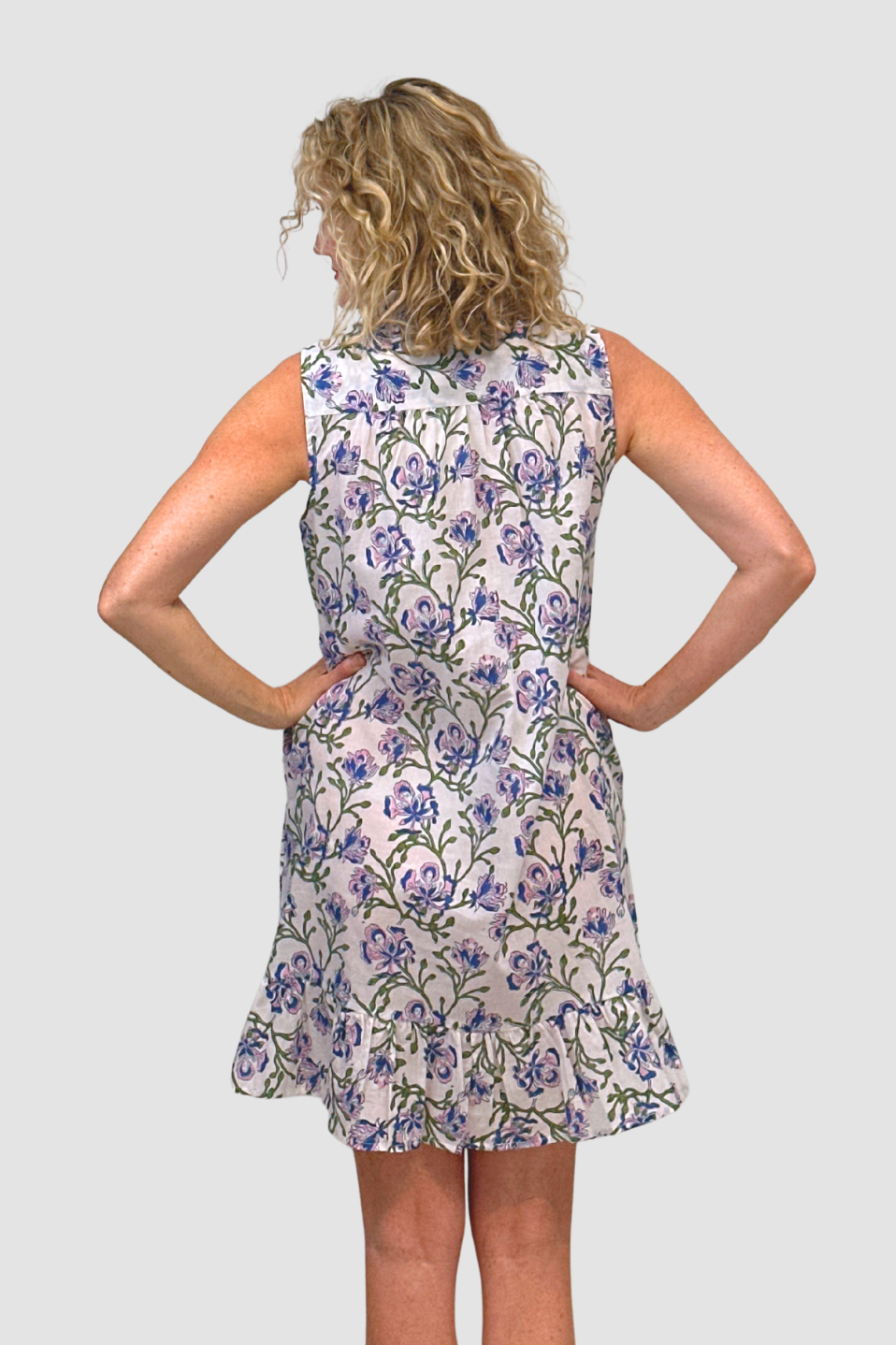 Woman wearing a floral dress/Blue Orchid Garden Dress against a plain background