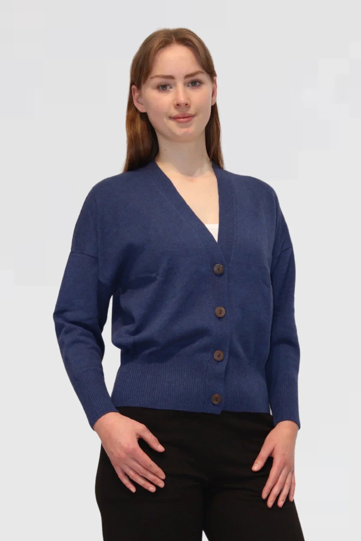 Woman wearing a blue cardigan with brown buttons on a white background