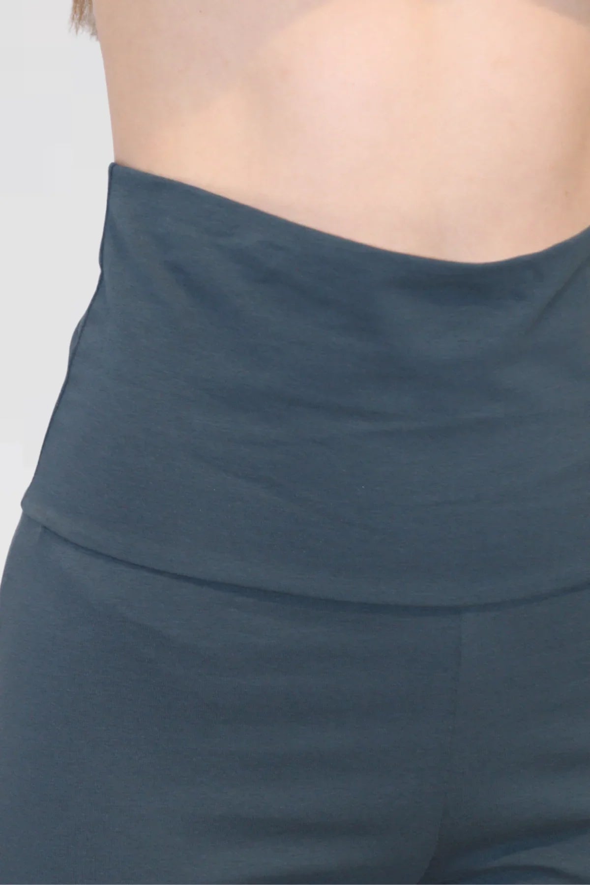 Close-up of a person wearing a blue yoga pants on a light grey background