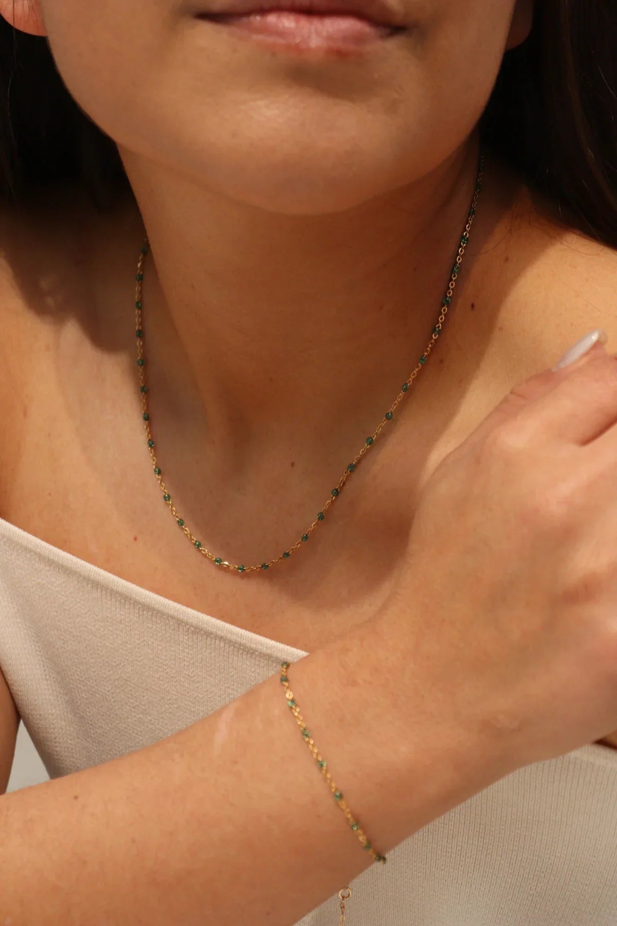 Close-up of a person wearing a delicate gold necklace and bracelet.
