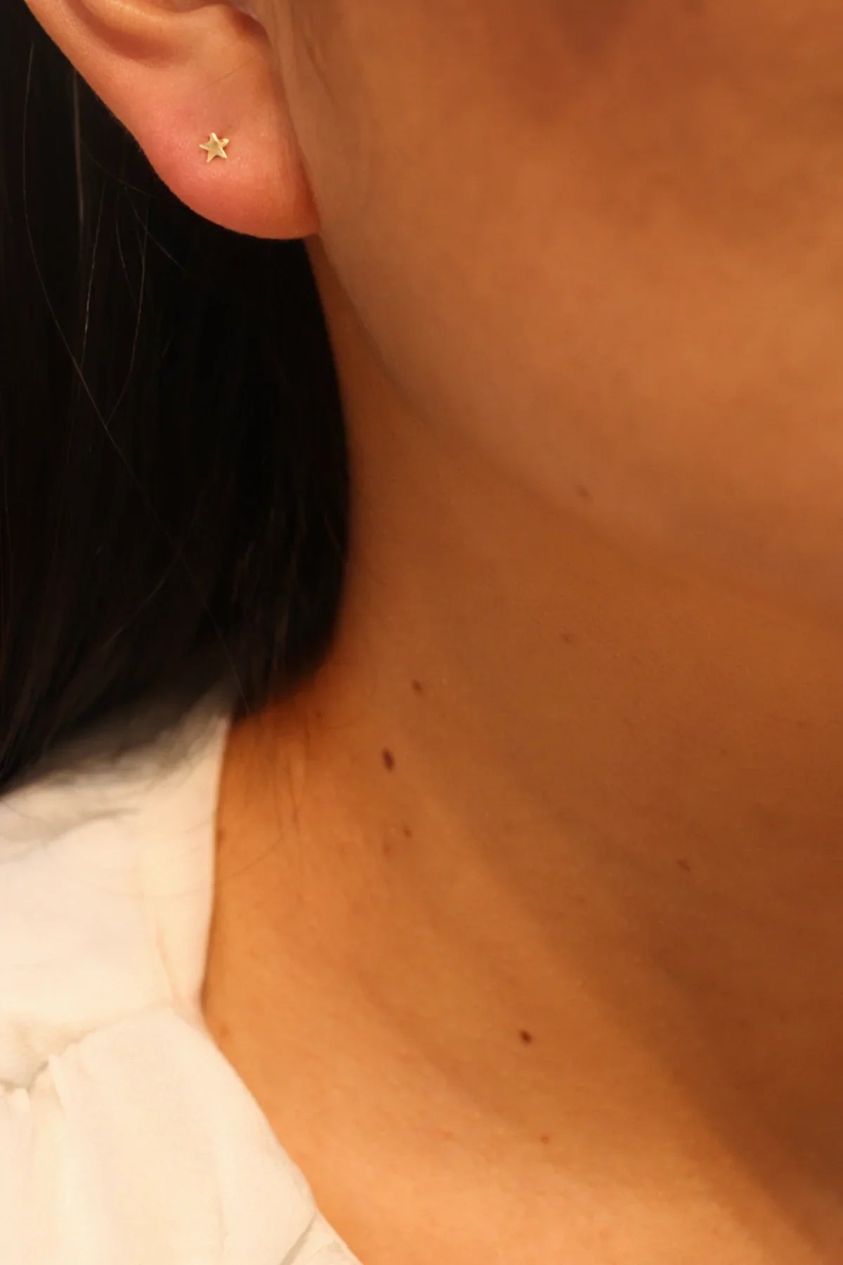 Close-up of an ear with a gold star-shaped earring.
