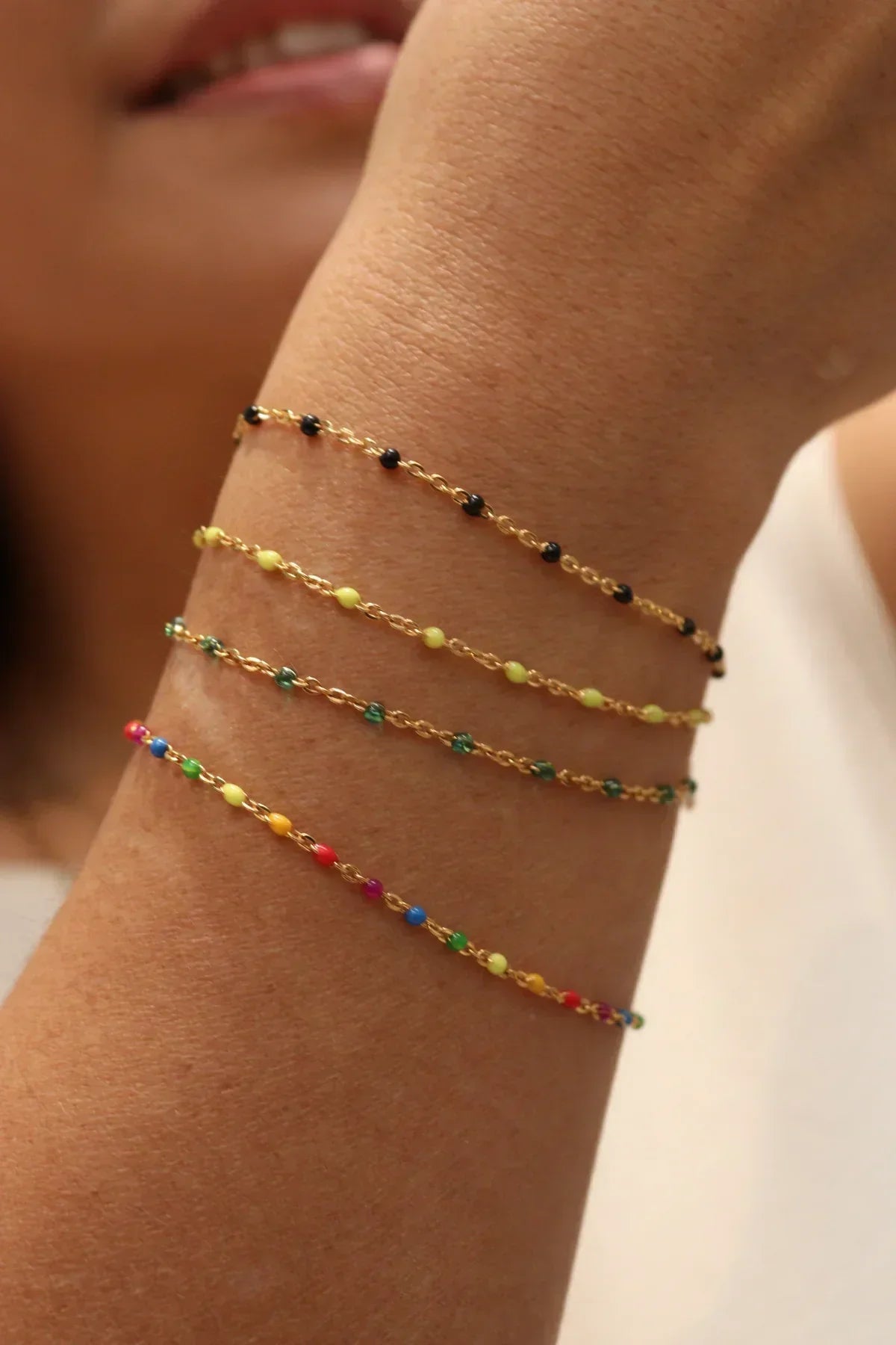 Close-up of a wrist wearing two colorful beaded bracelets on a neutral background