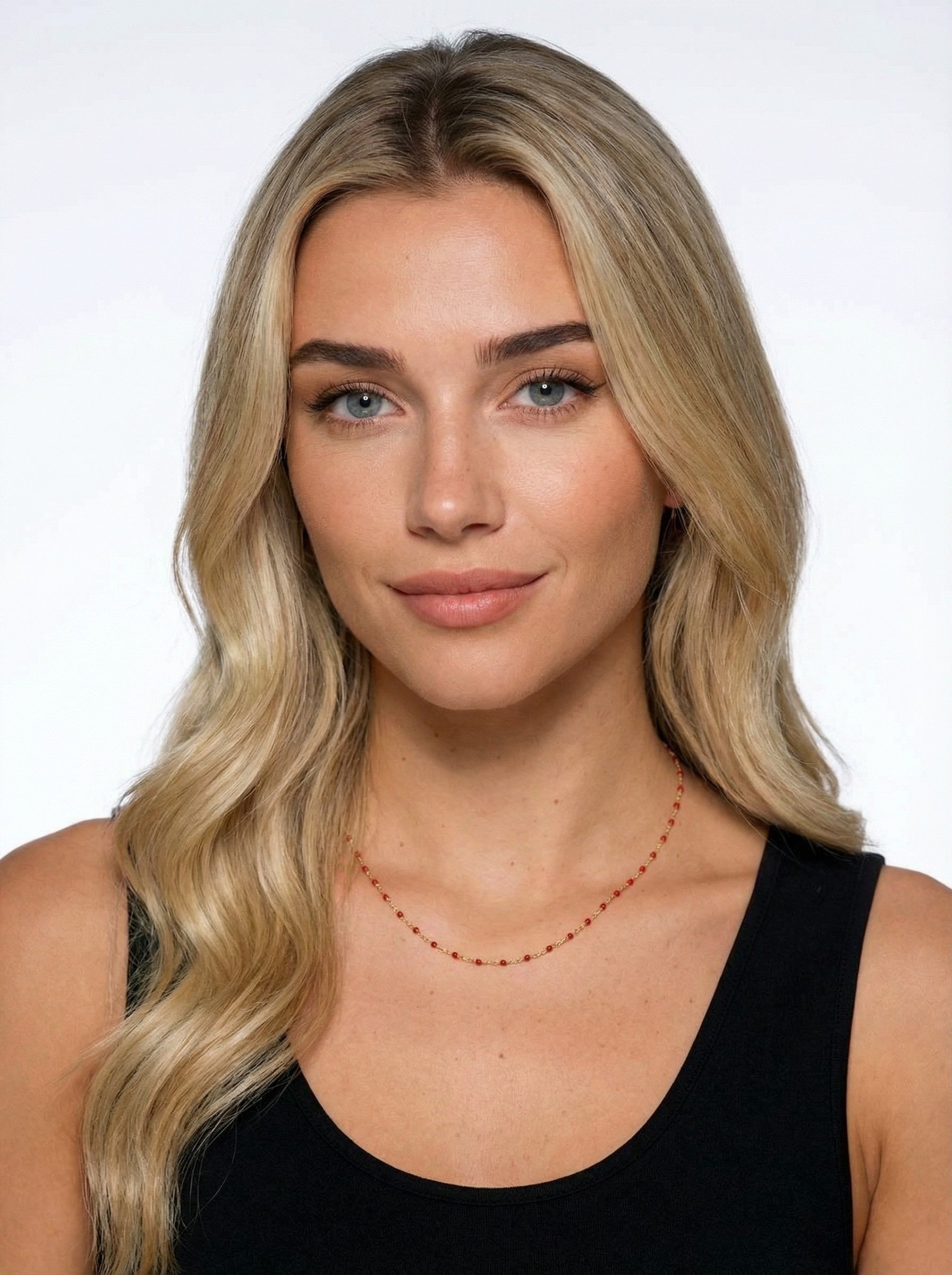 Woman with blonde hair wearing a black top and Crimson Satellite Necklace on a white background
