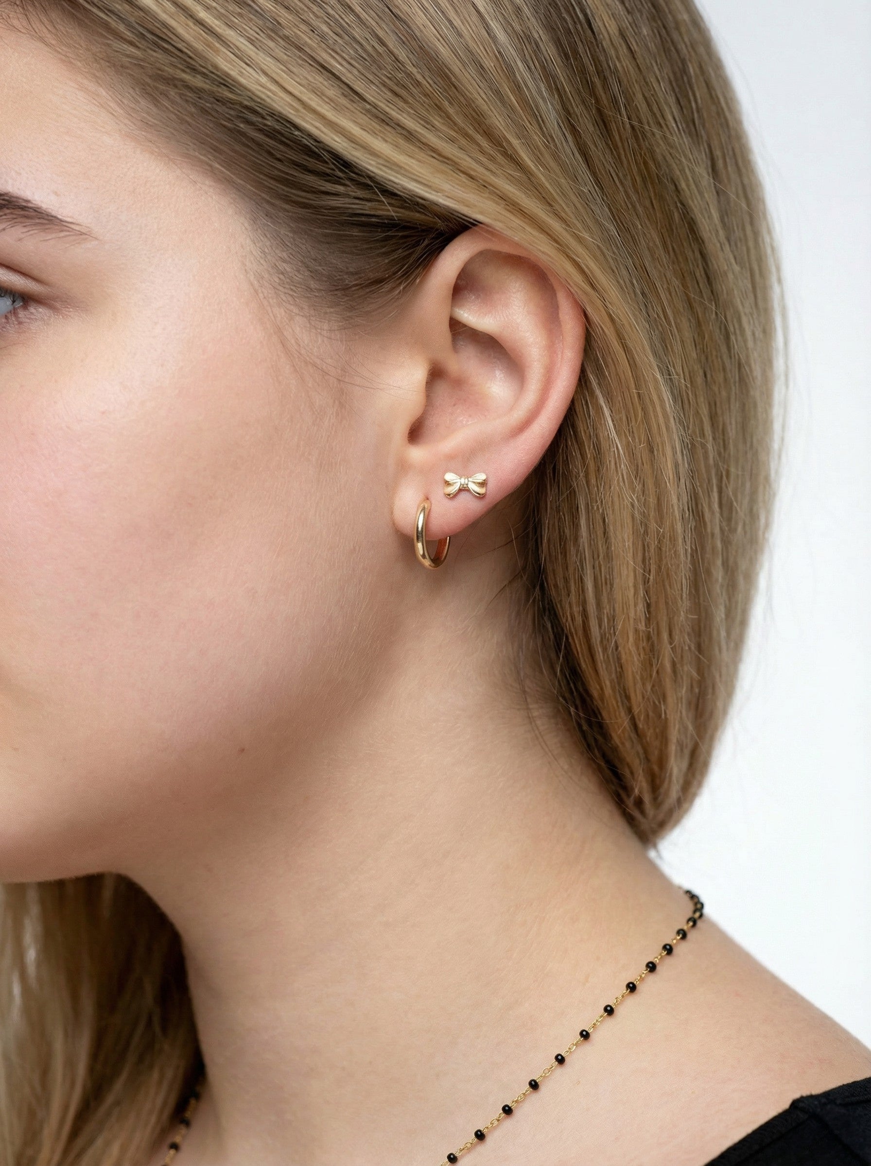 Model is wearing a pair Gold Bow Studs.