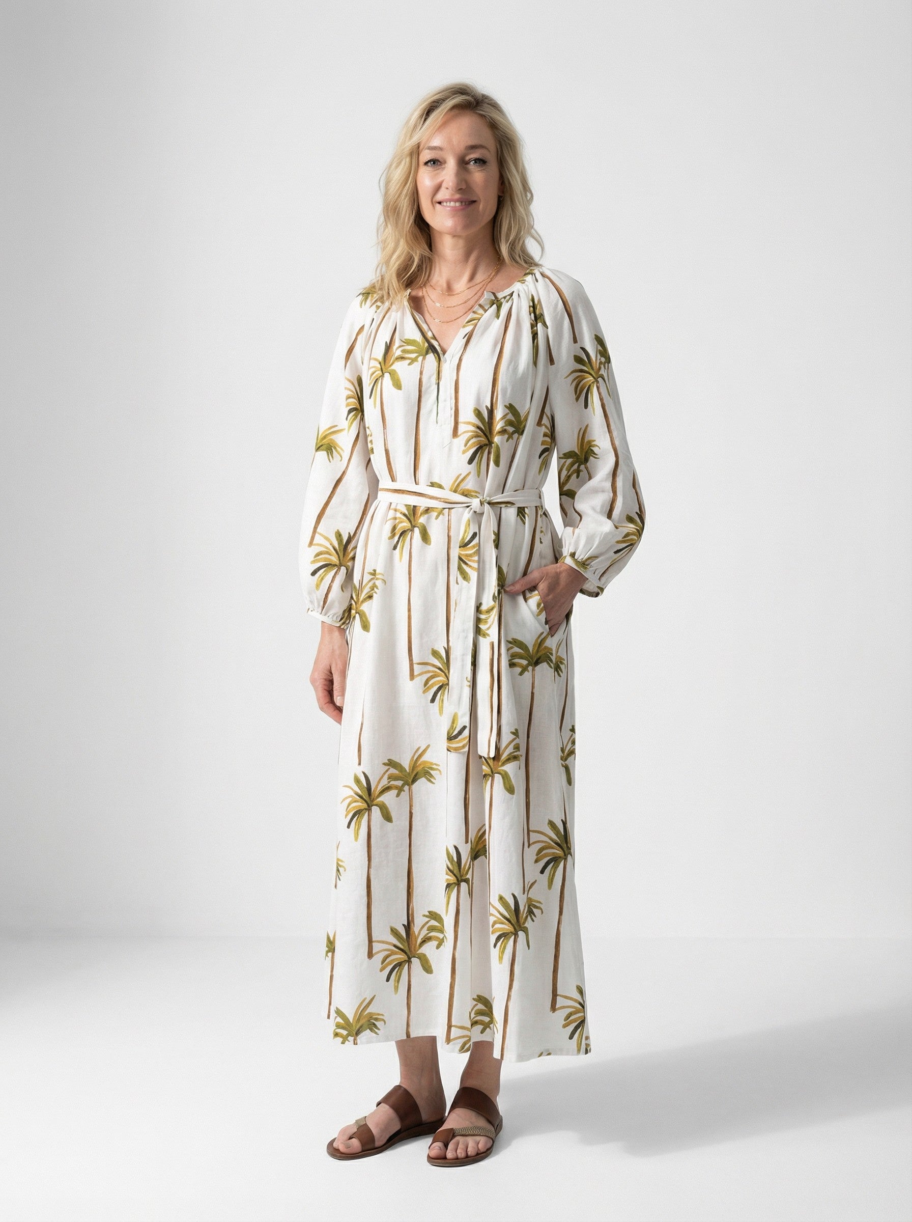 Woman wearing a Golden Oasis Palm Dress against a white background
