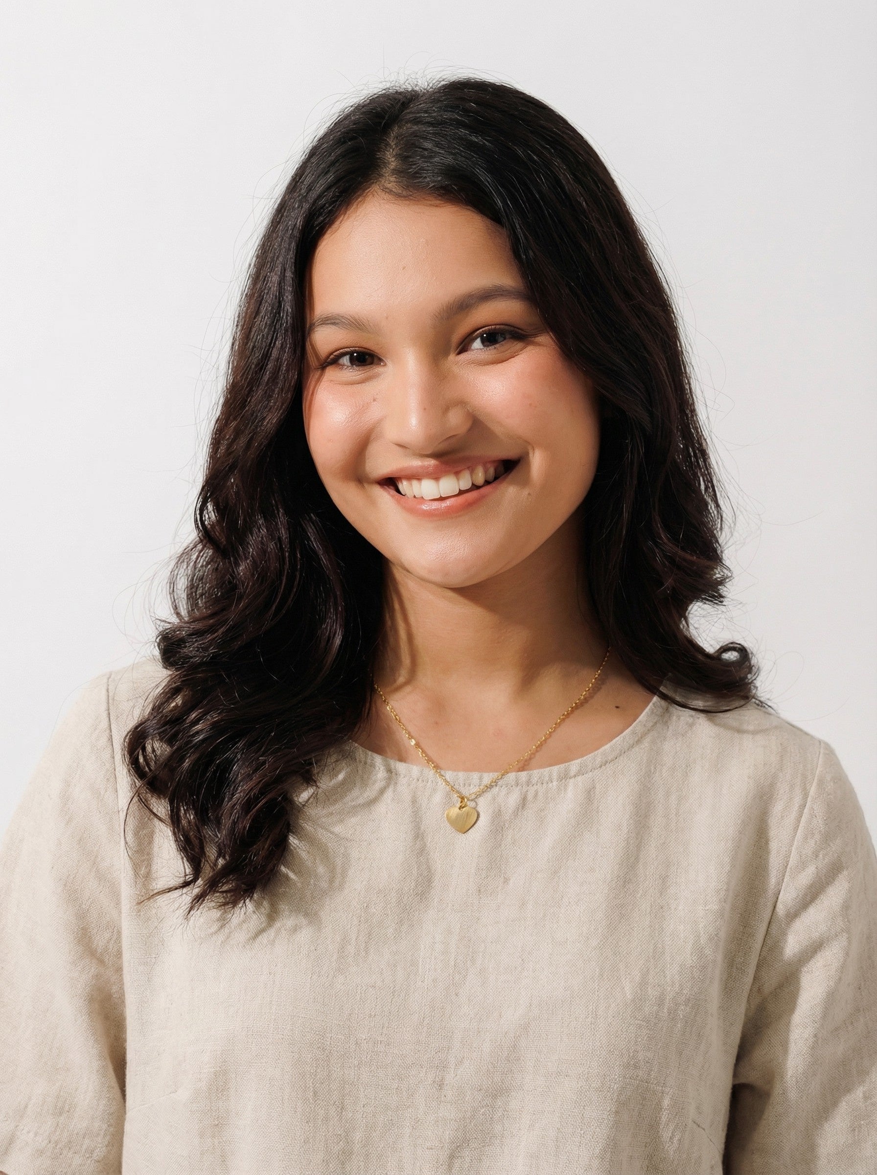 Woman wearing ethical everyday gold heart pendant necklace and linen top, Reca jewelry collection