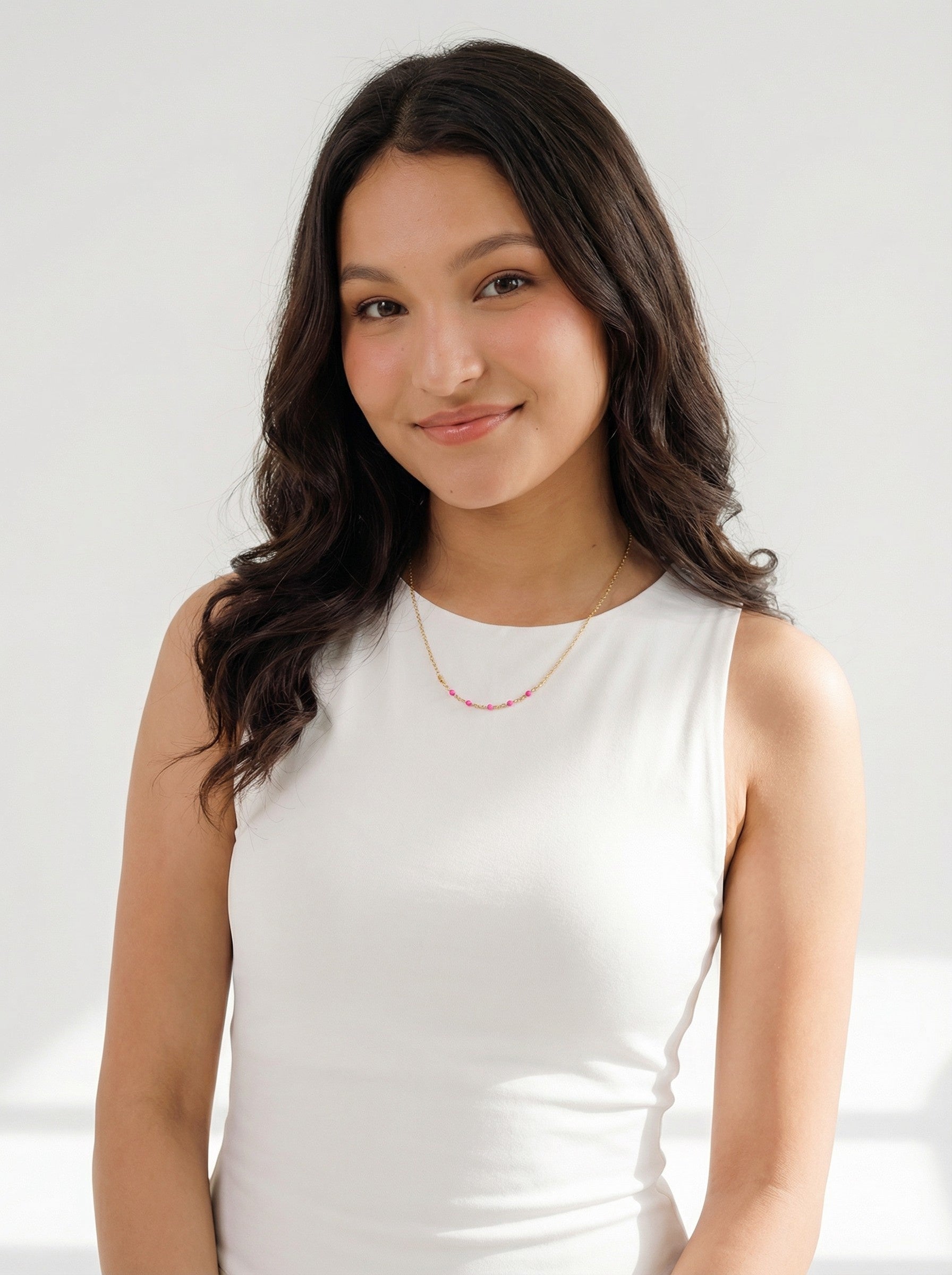 Woman wearing a white sleeveless top and Hot Pink Enamel Satellite Necklace against a plain background