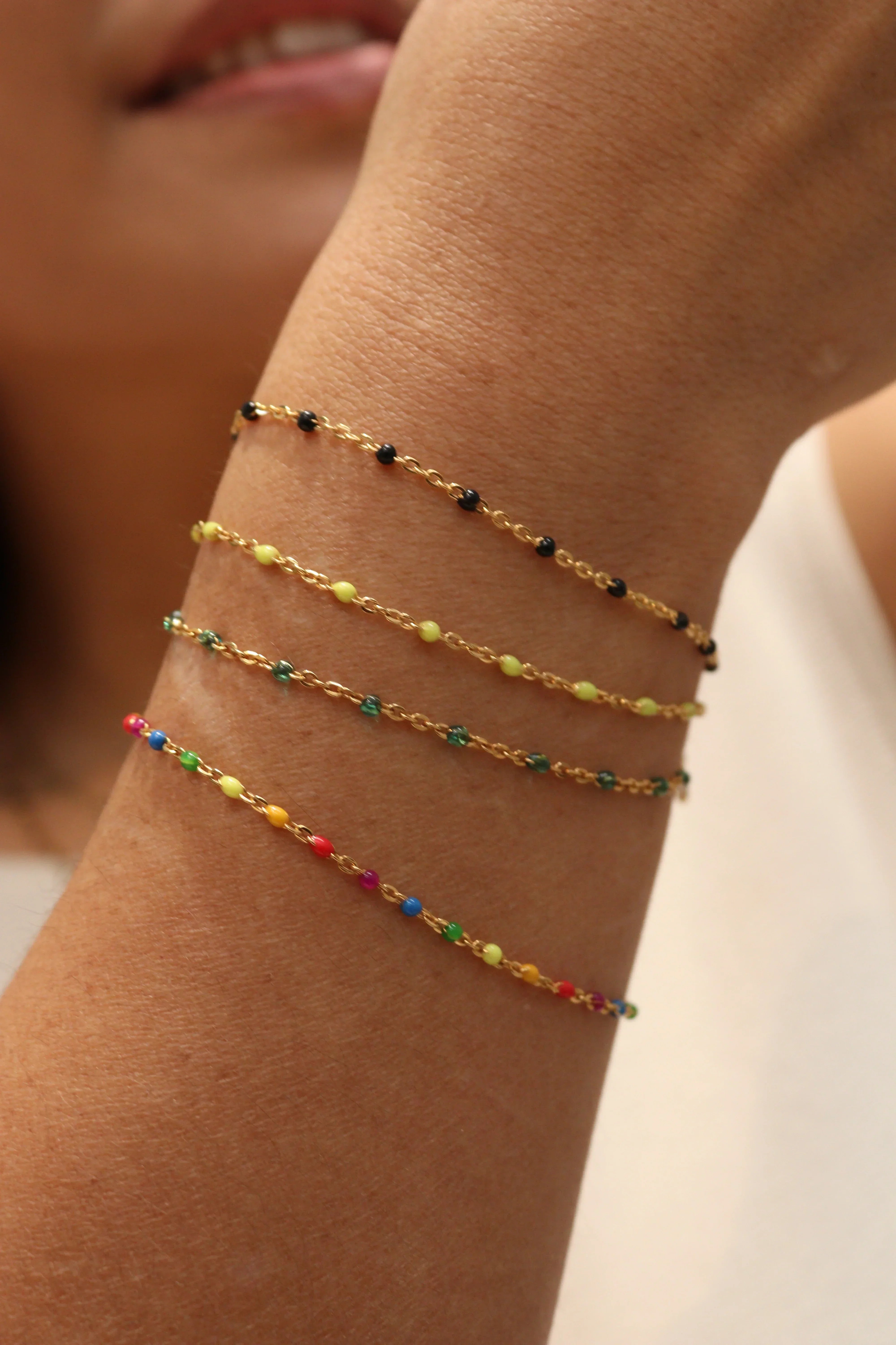 Close-up of a wrist wearing colorful beaded bracelets on a blurred background