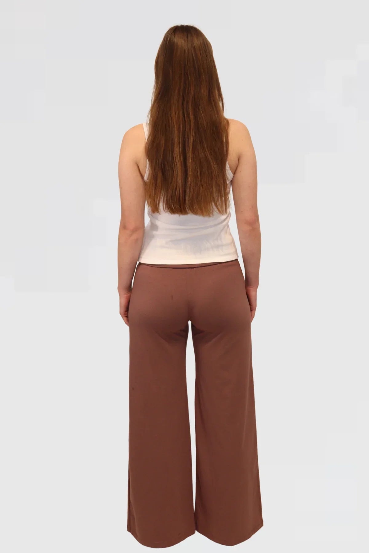 Woman wearing a beige sleeveless top and Leisure Lux Pants - Mocha Mousse on a white background