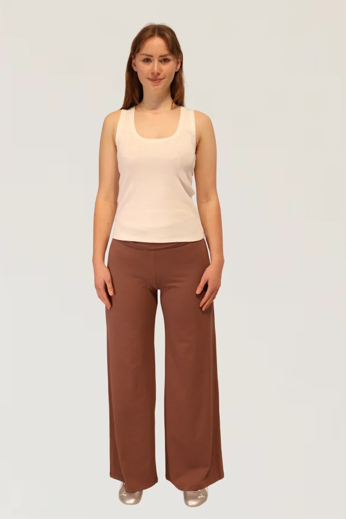 Woman wearing a beige sleeveless top and Leisure Lux Pants - Mocha Mousse on a white background
