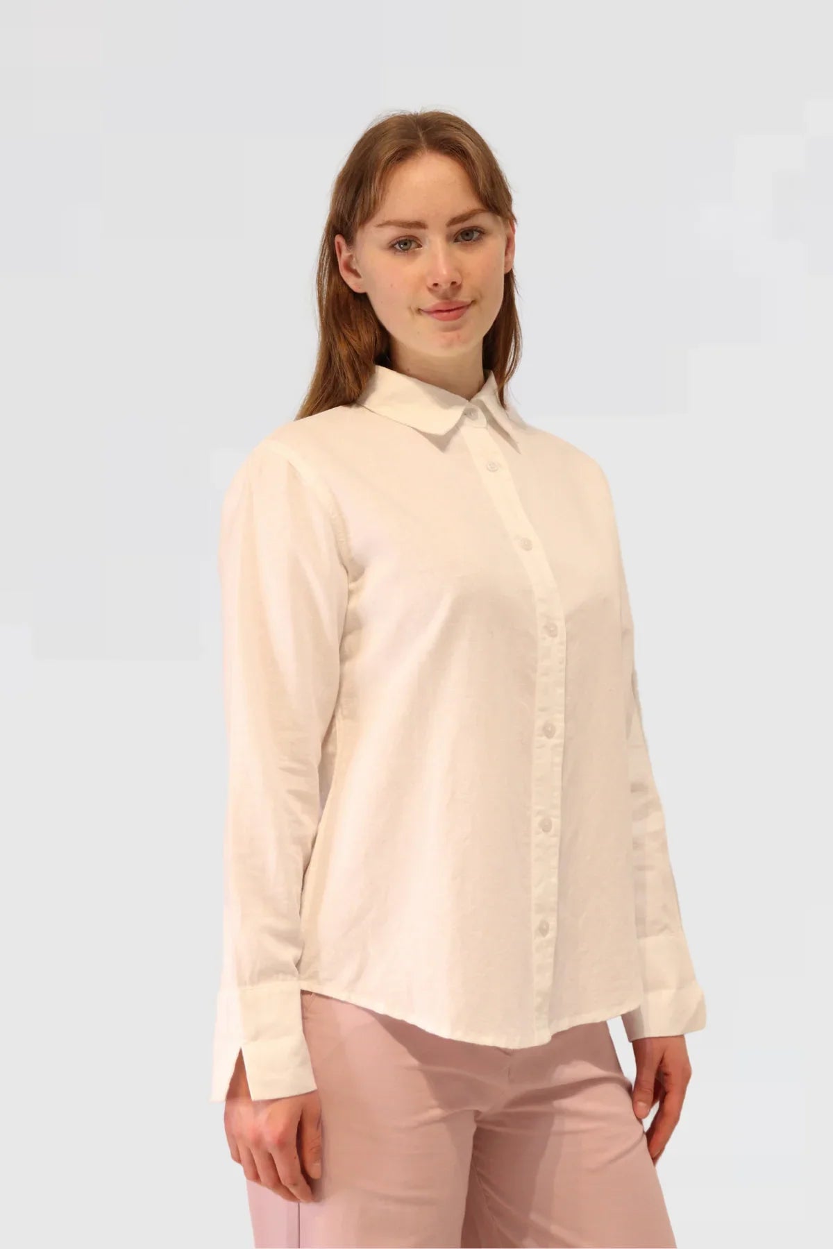 Woman wearing a white linen blouse against a white background