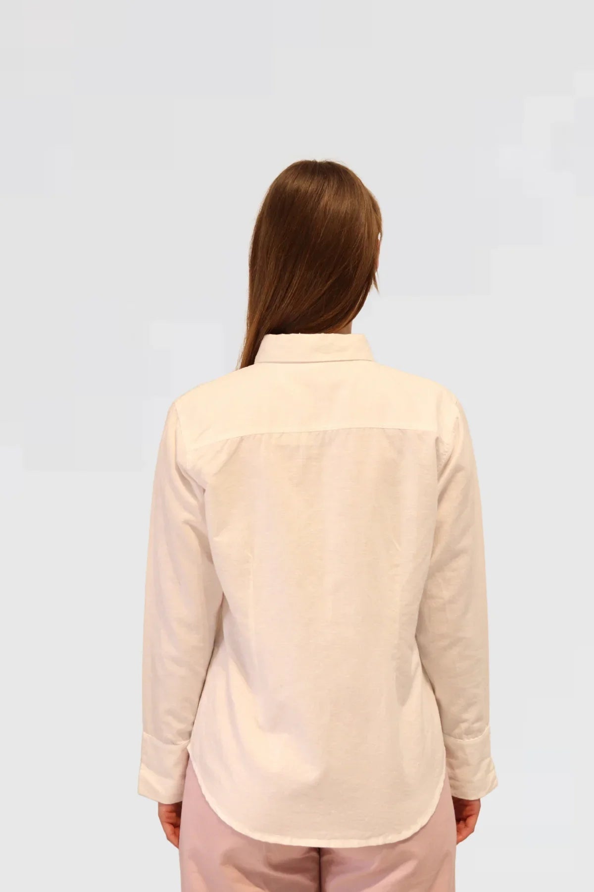 the back of Woman wearing a Linen Shirt - White and dusty pink pants on a white background