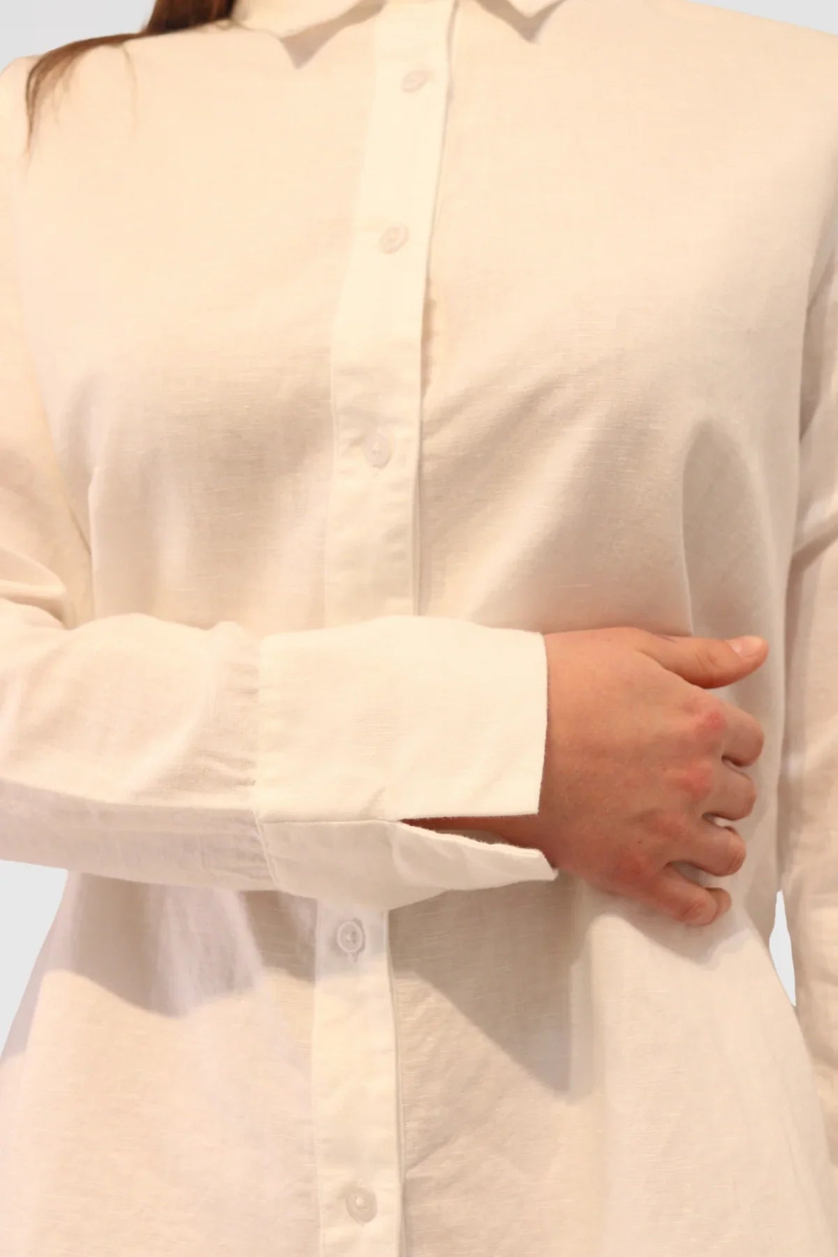 Close-up of a person wearing a Linen Shirt - White with a plain background