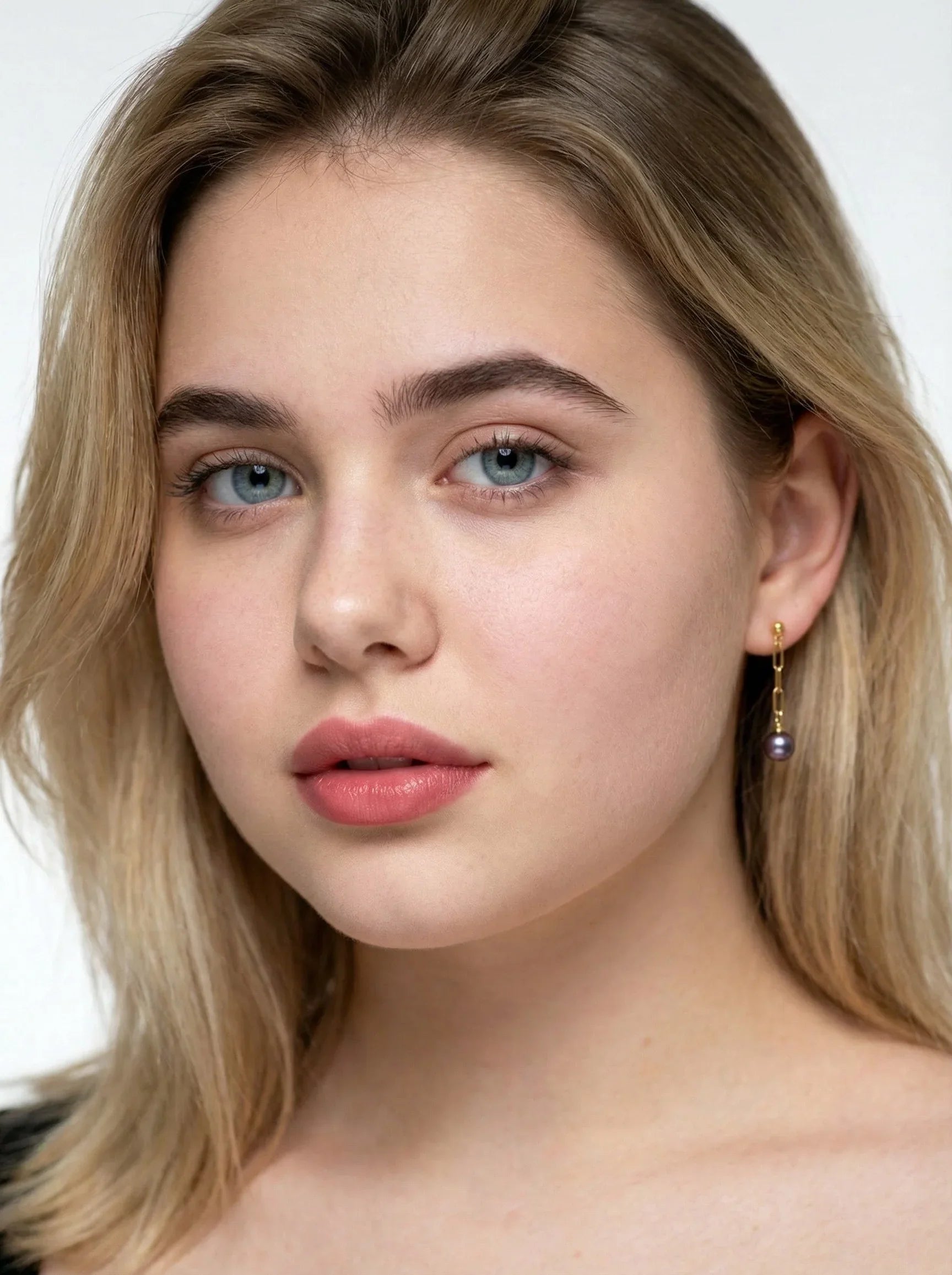Close-up of a person with blonde hair and blue eyes wearing earrings.