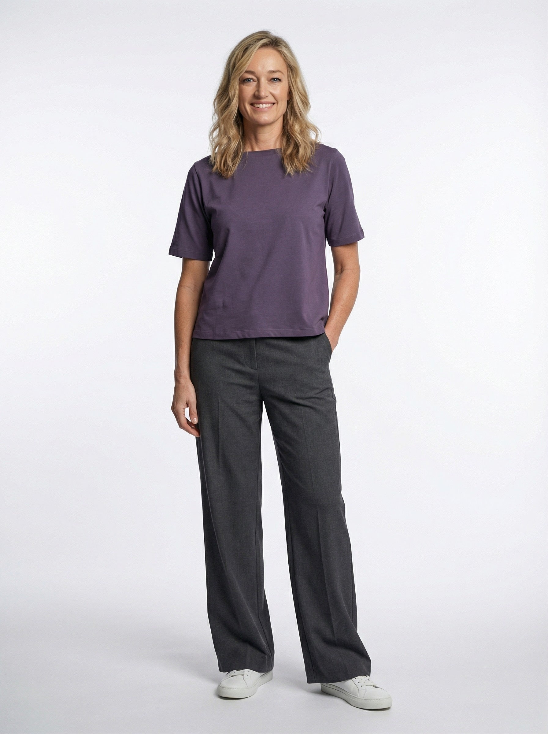 Woman wearing a Organic Flex Crew Tee - Prune and gray pants on a white background