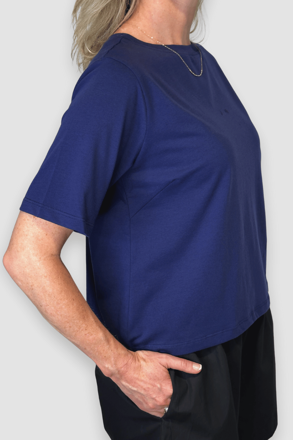 Person wearing a blue shirt and black pants against a white background