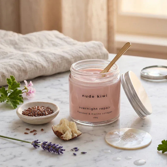 Nude Kiwi Overnight Repair open jar with gold spoon on marble, surrounded by flaxseeds, lavender, and natural ingredients