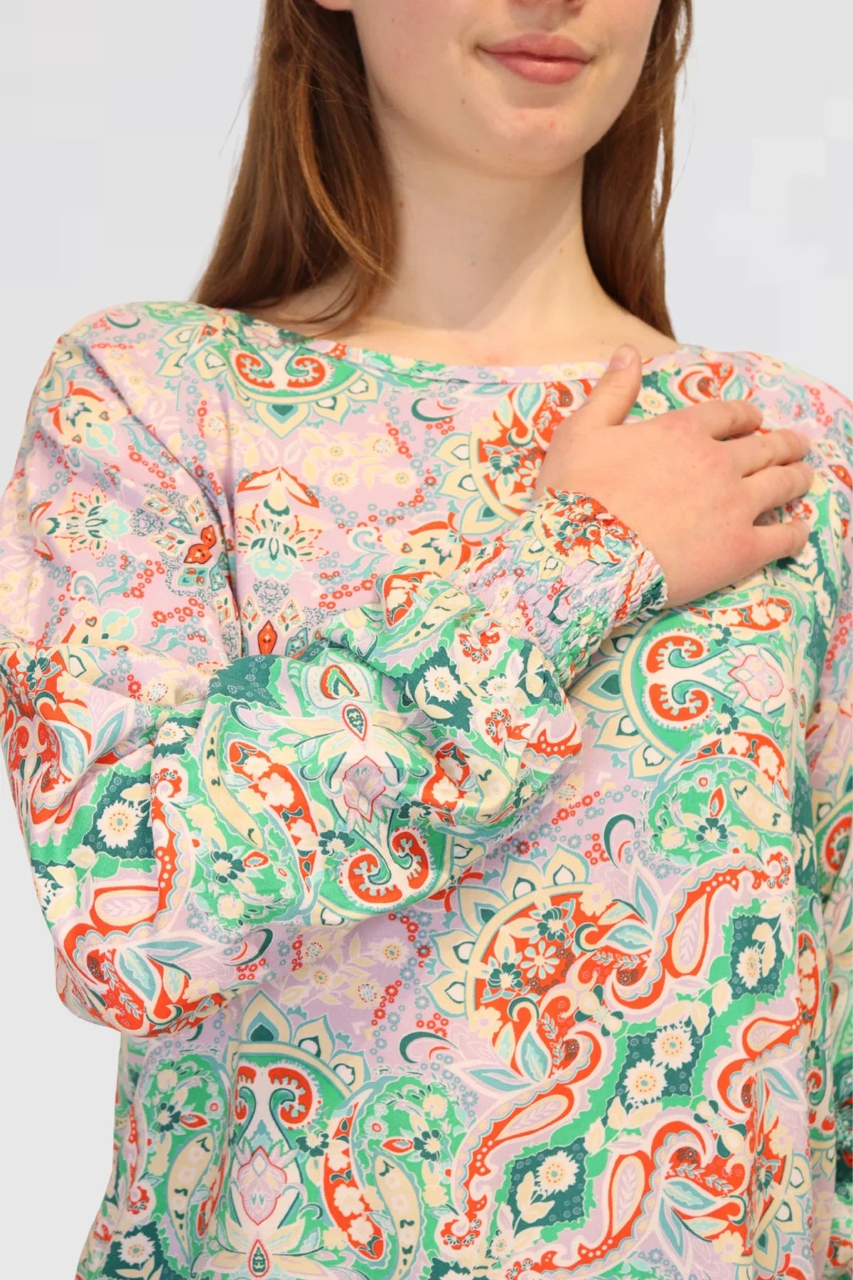 Woman wearing a colorful patterned blouse against a plain background